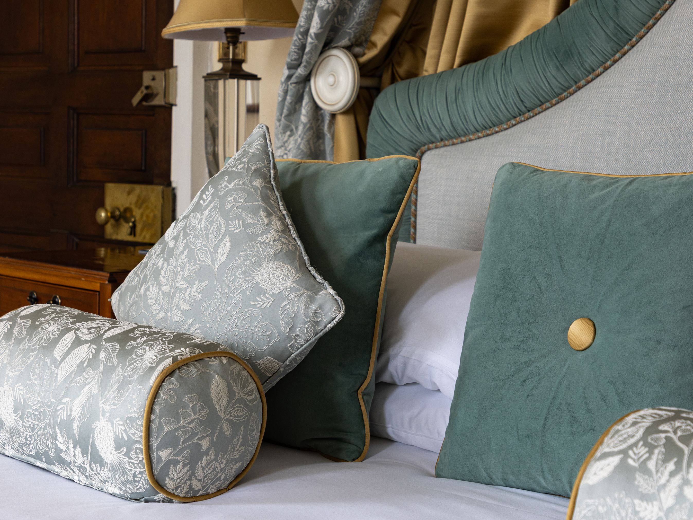 Luxury bed with velvet and patterned pillows in an elegantly decorated room
