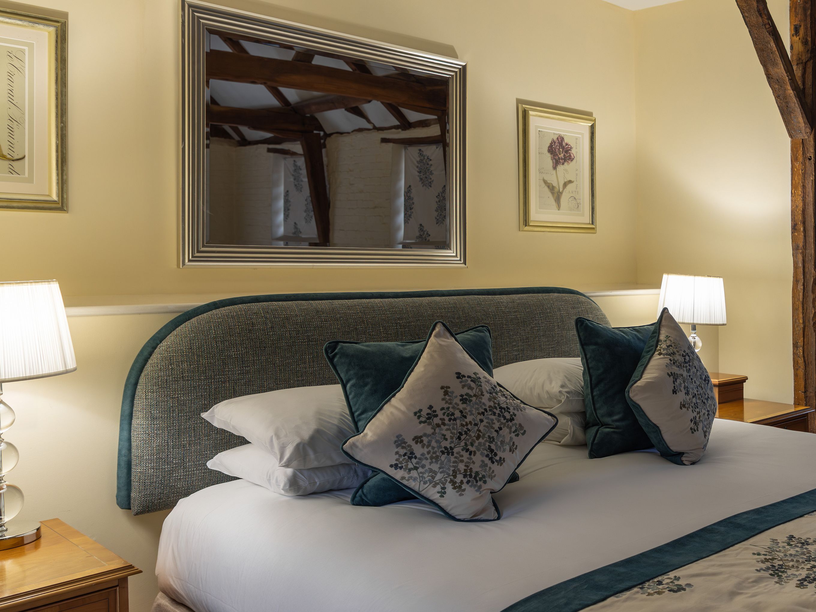 Cozy bedroom with a double bed, decorative pillows, lamps, and framed art on the walls