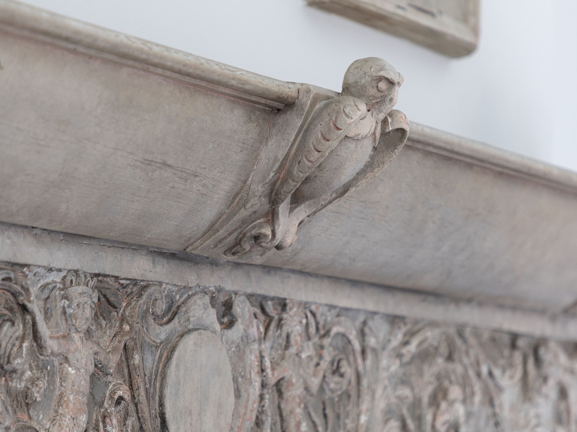 Close-up of an ornate stone fireplace mantle with detailed carvings, including a sculpted owl.