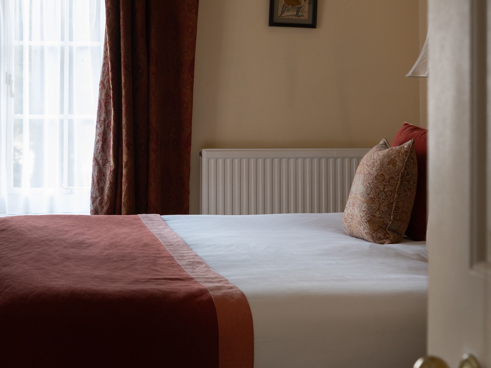 Cozy bedroom with rustic wooden ceiling beams and a bed with red and beige bedding