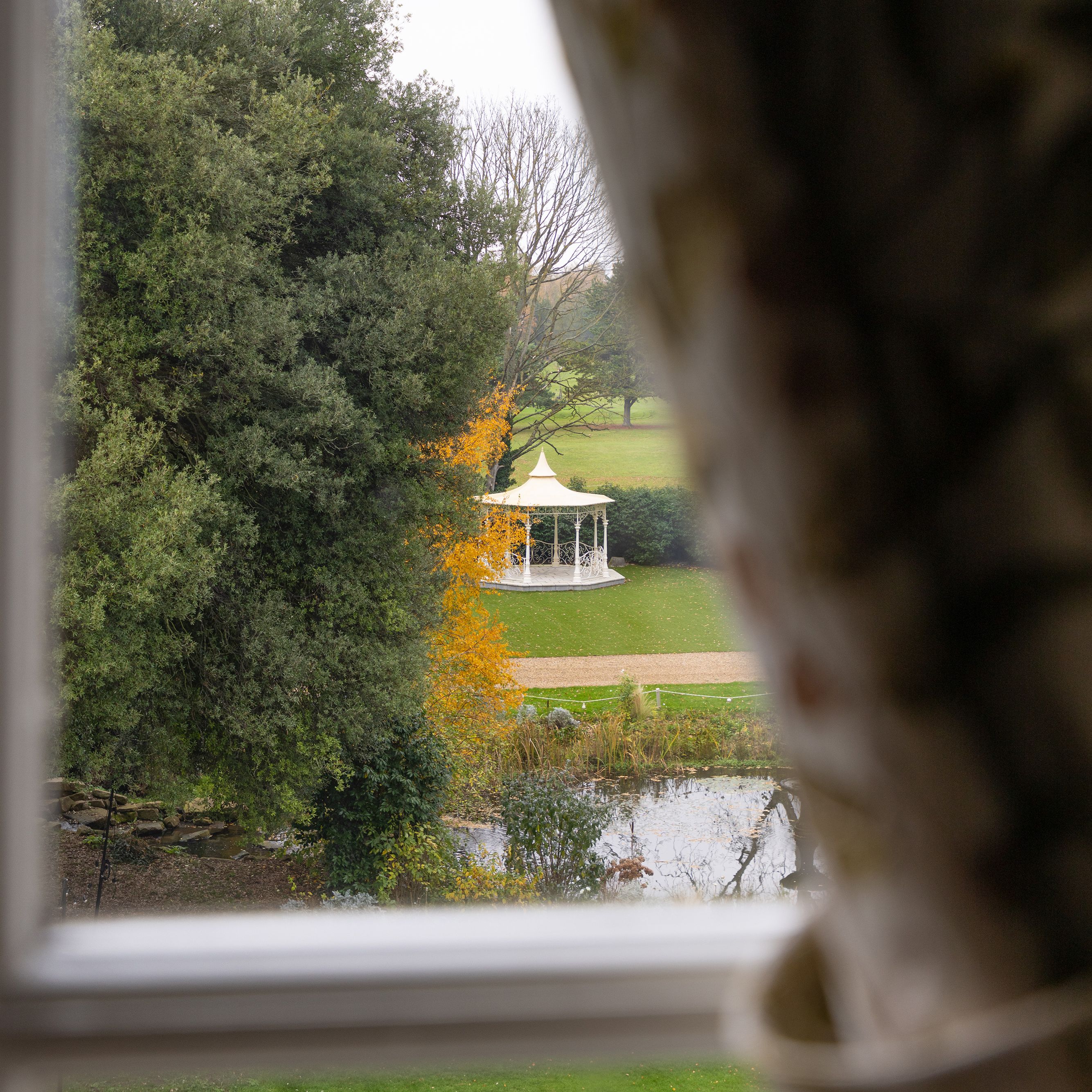White gazebo in a park seen through a window