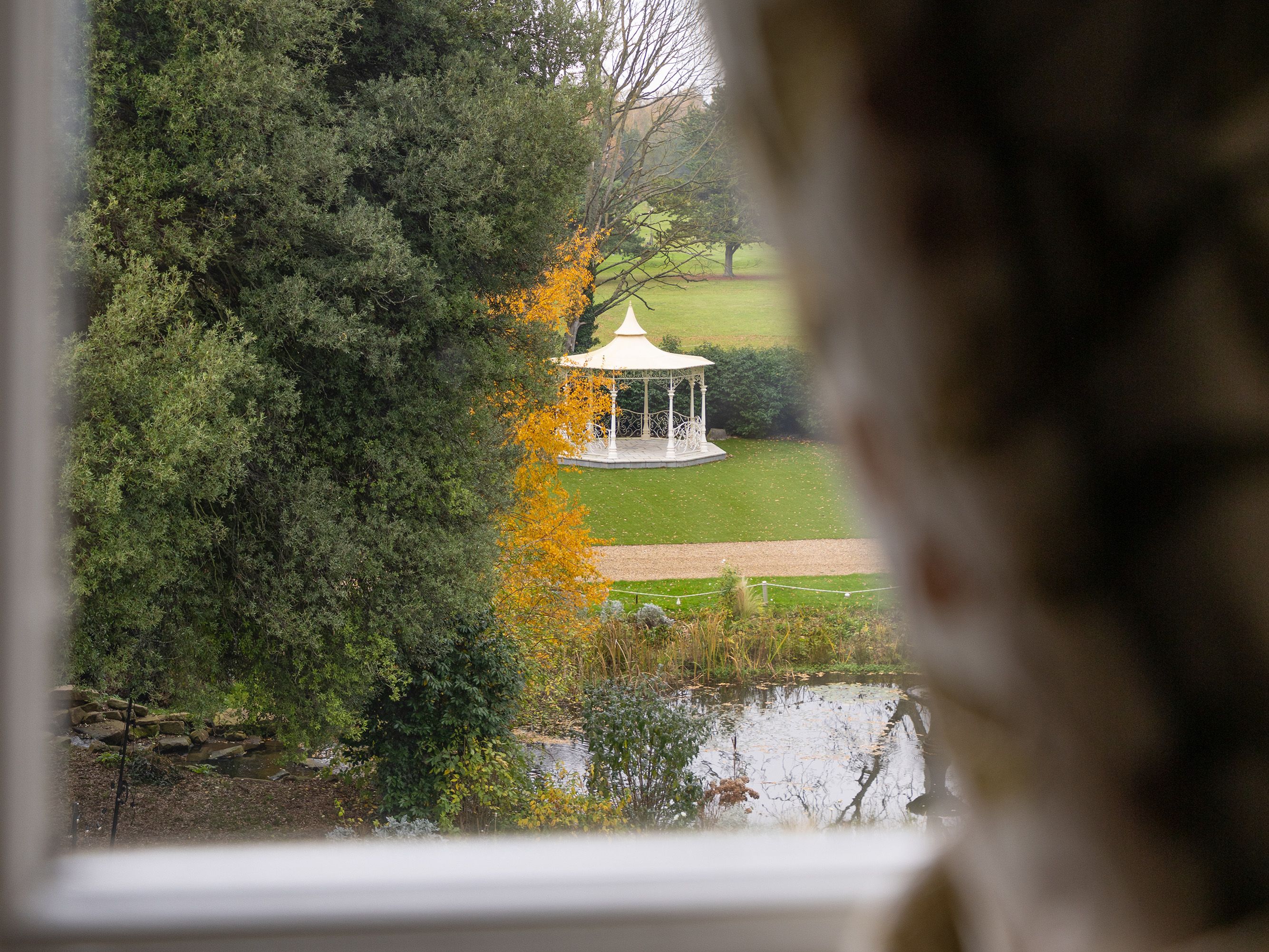 White gazebo in a park seen through a window