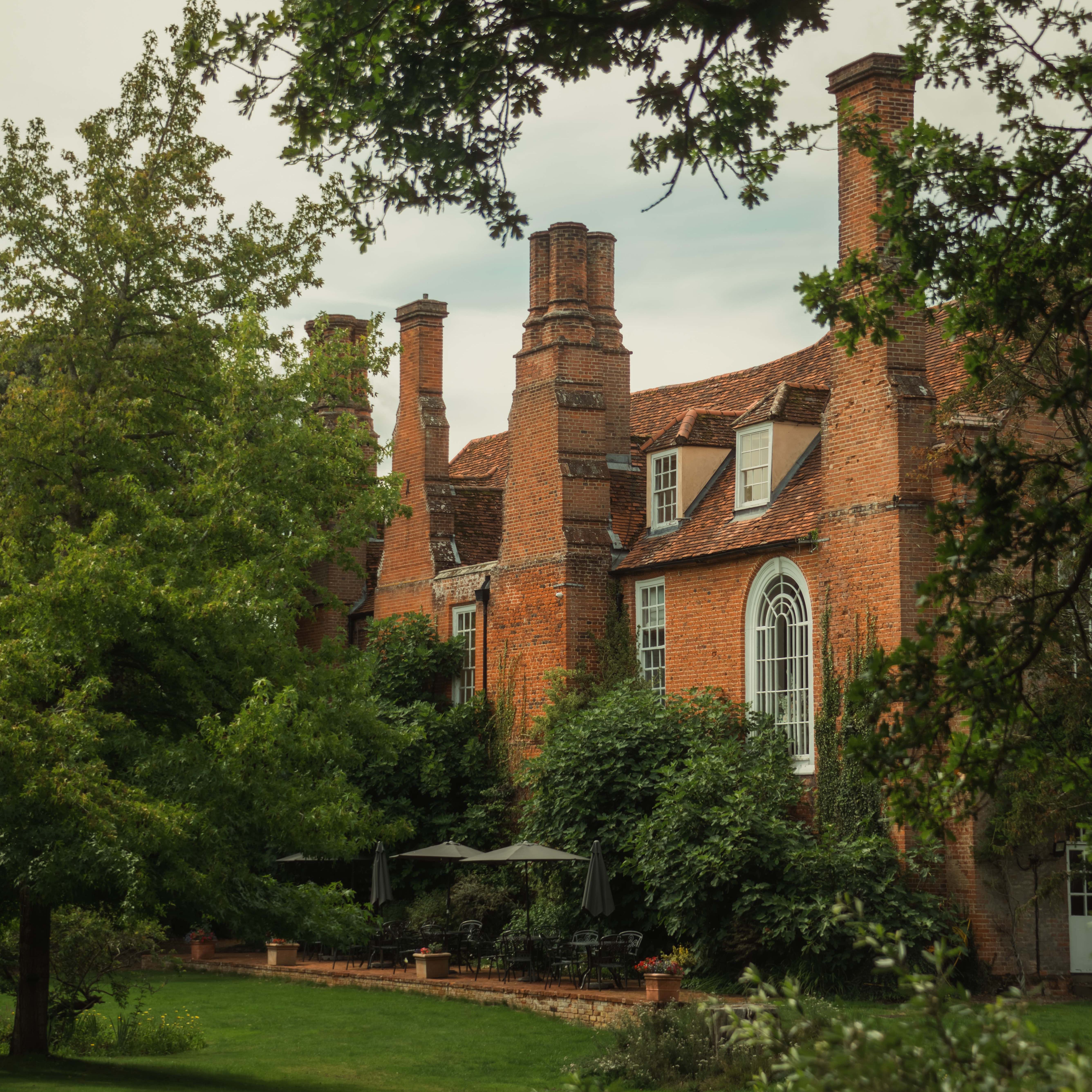 Historic brick mansion surrounded by lush green gardens and trees