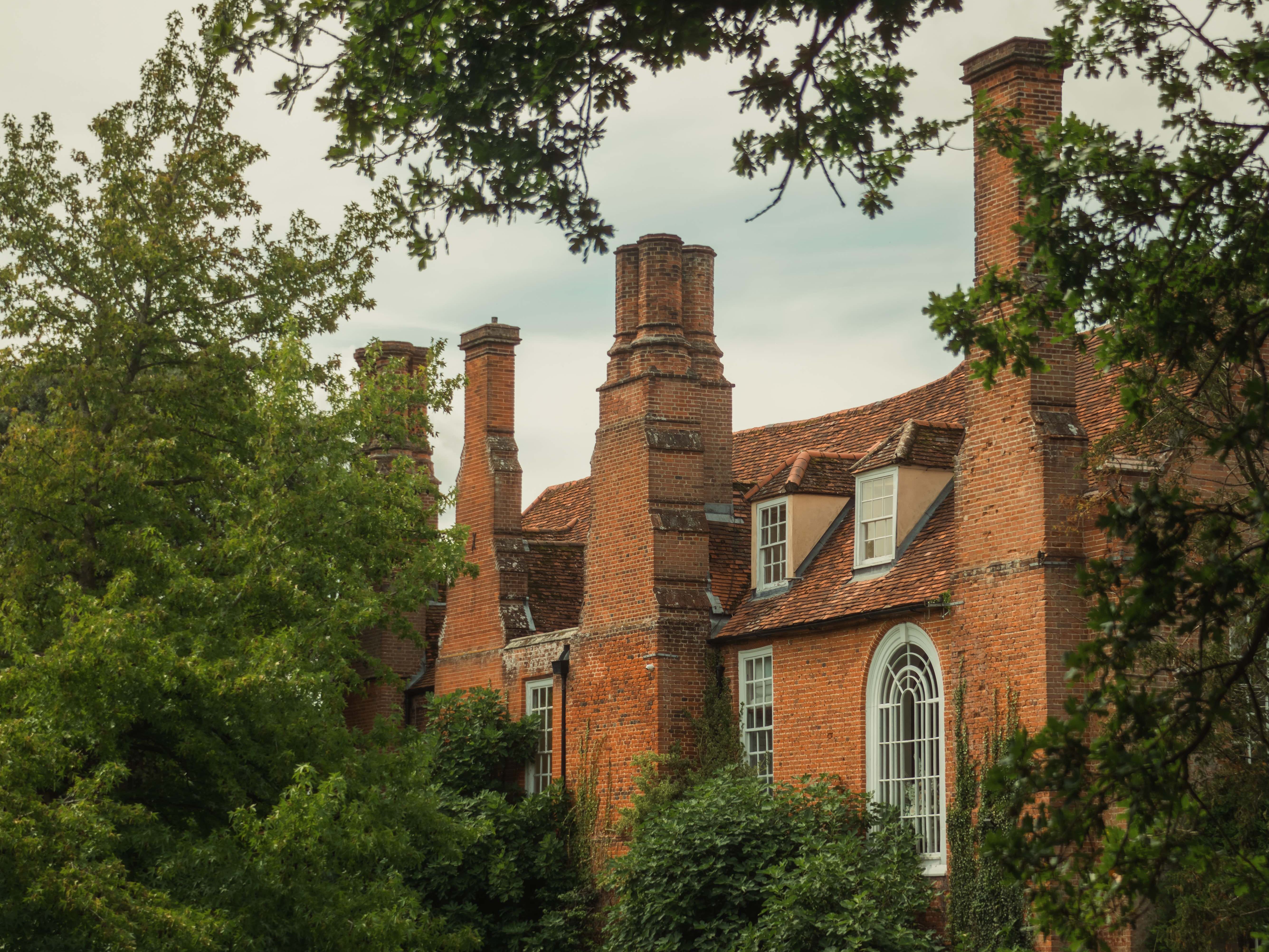 Historic brick mansion surrounded by lush green gardens and trees