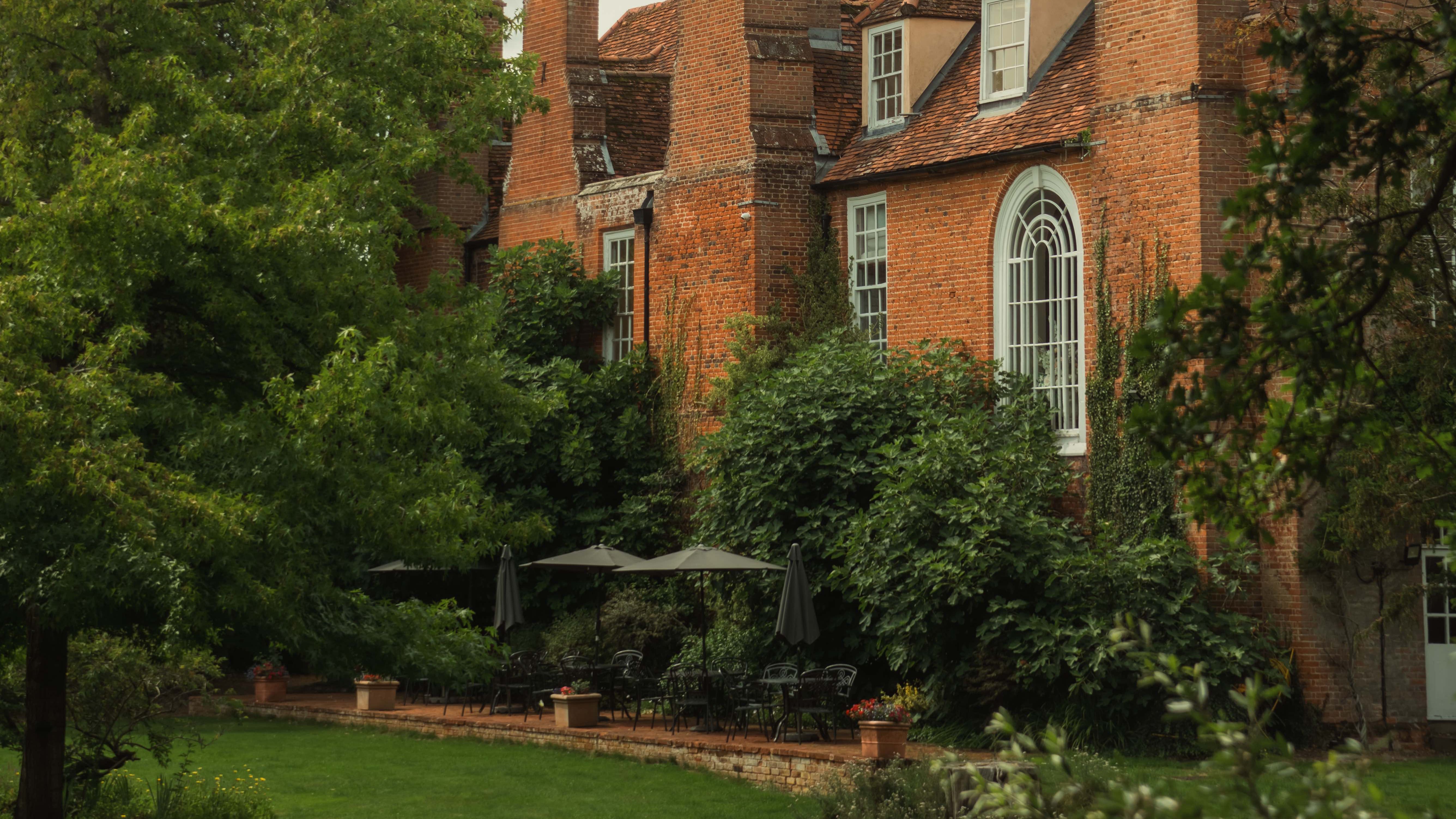 Historic brick mansion surrounded by lush green gardens and trees
