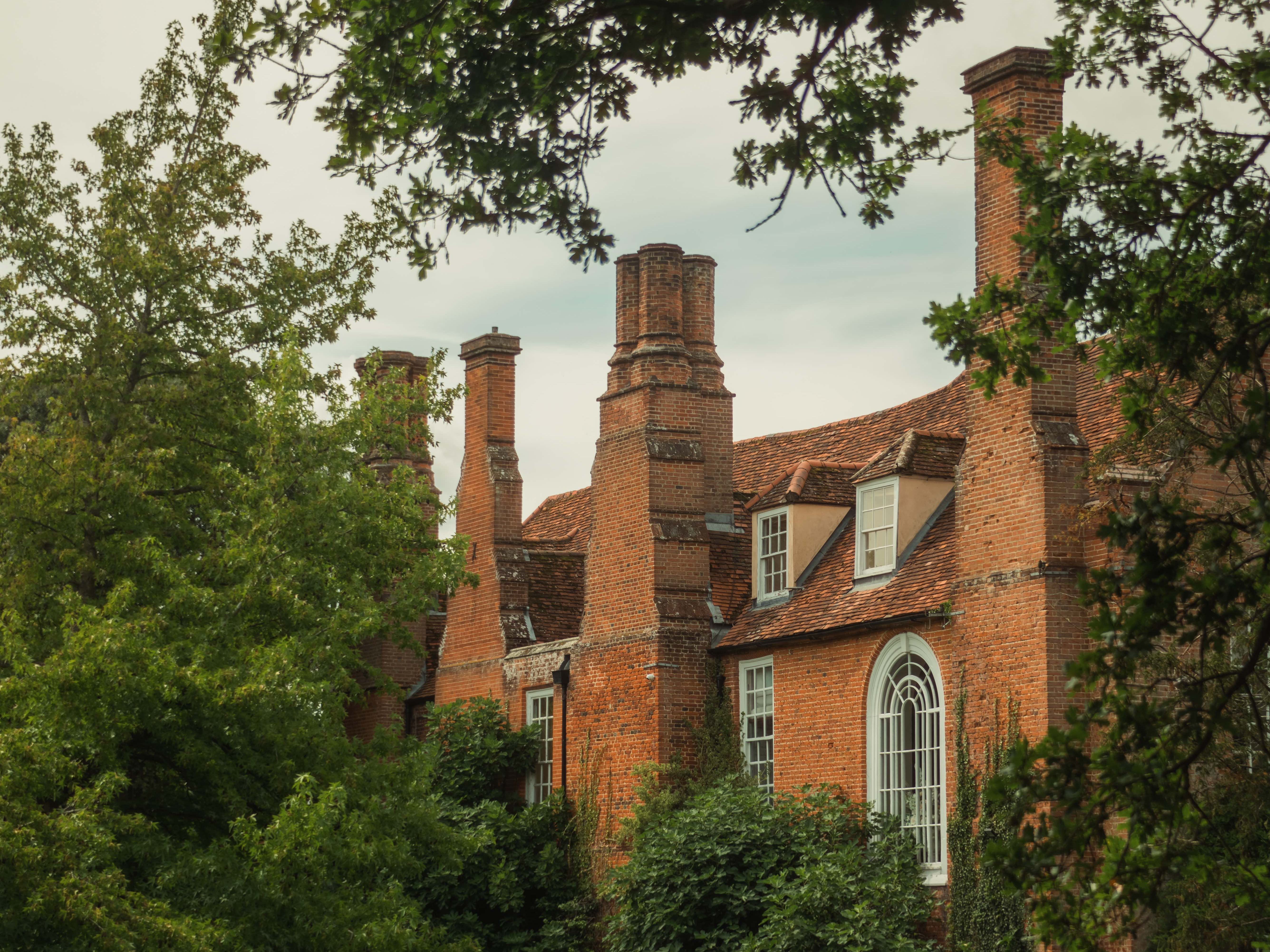 Historic brick mansion surrounded by lush green gardens and trees