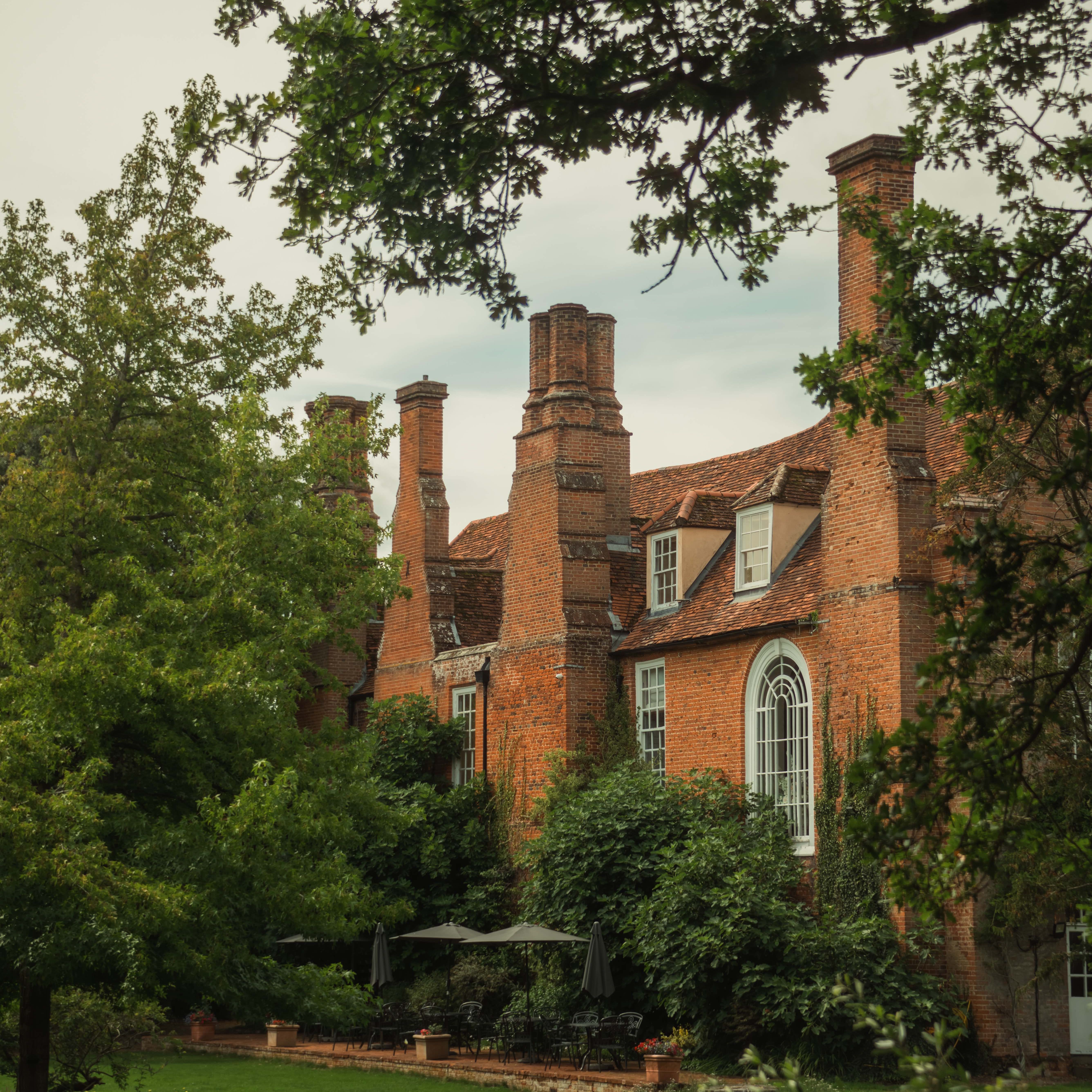 Historic brick mansion surrounded by lush green gardens and trees