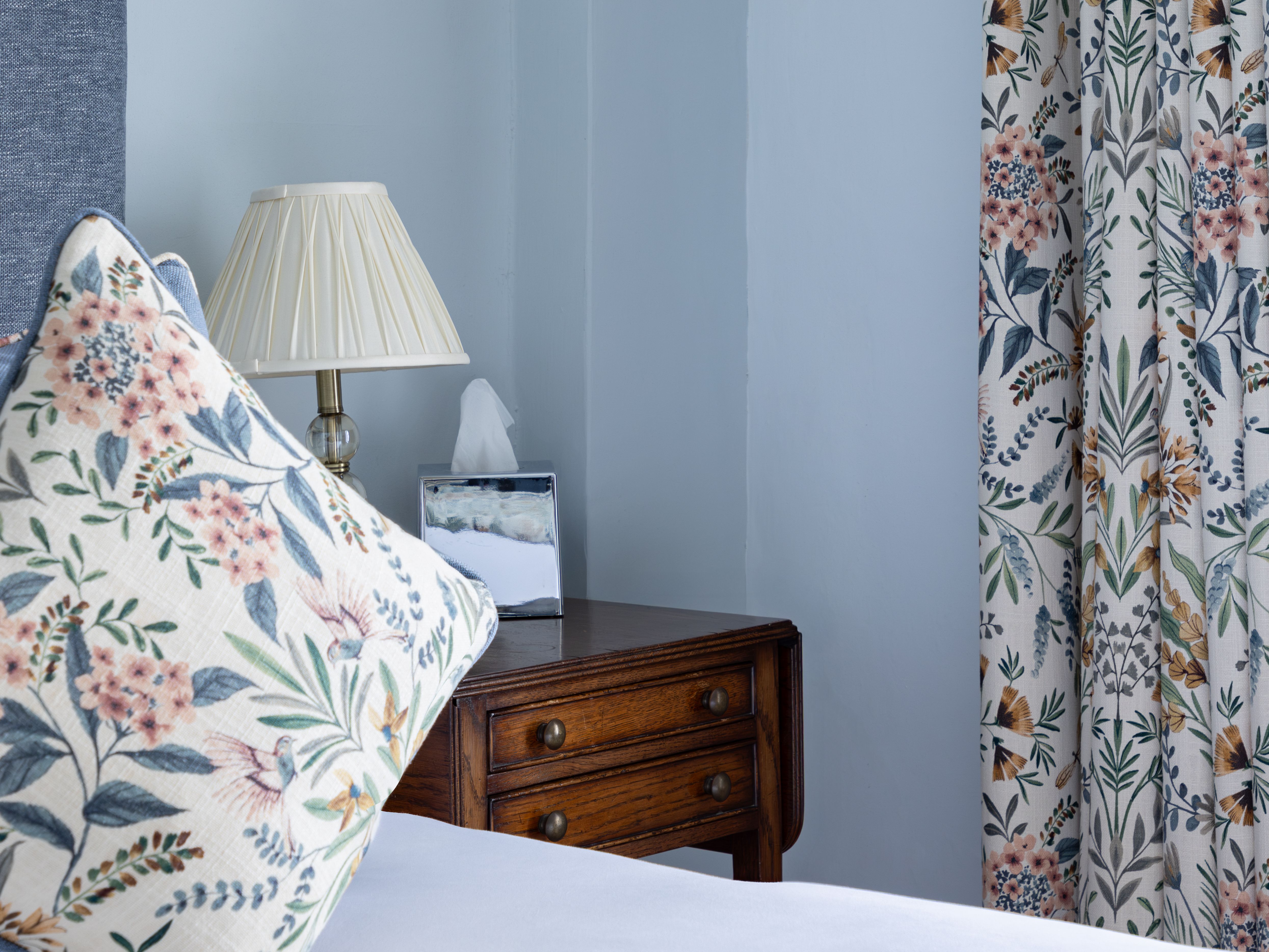 Bedroom with floral pillow, bedside lamp, and floral curtains