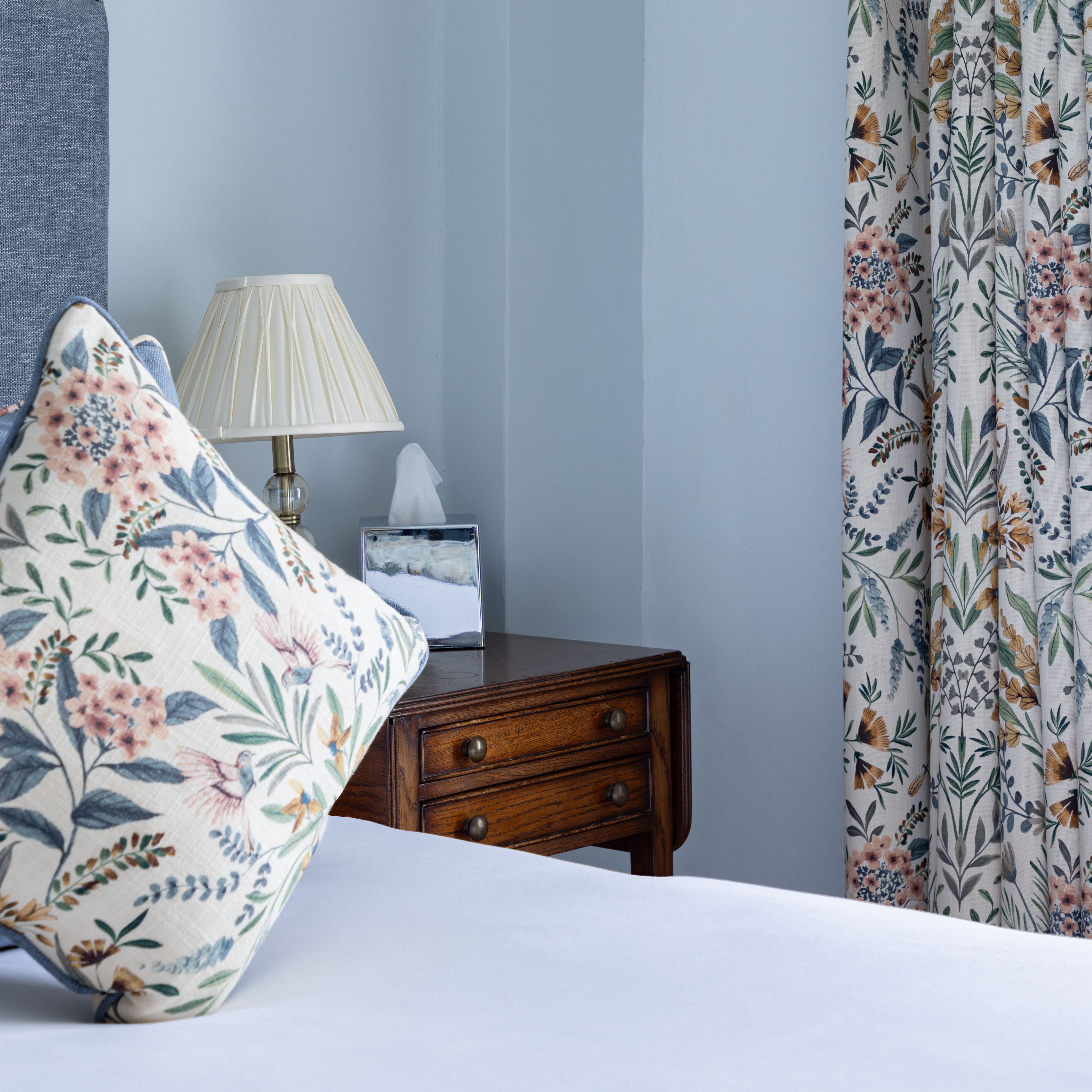 Bedroom with floral pillow, bedside lamp, and floral curtains