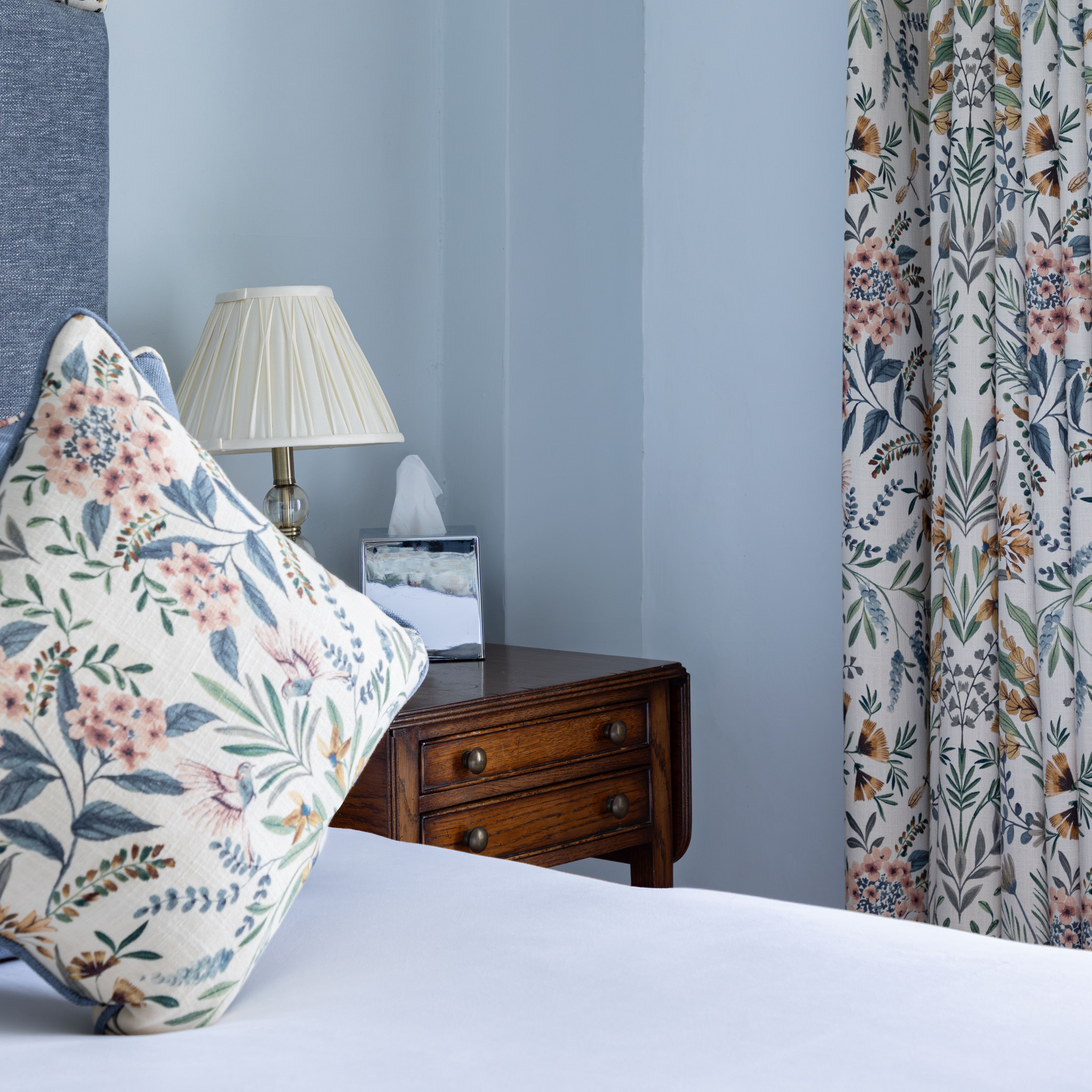 Bedroom with floral pillow, bedside lamp, and floral curtains