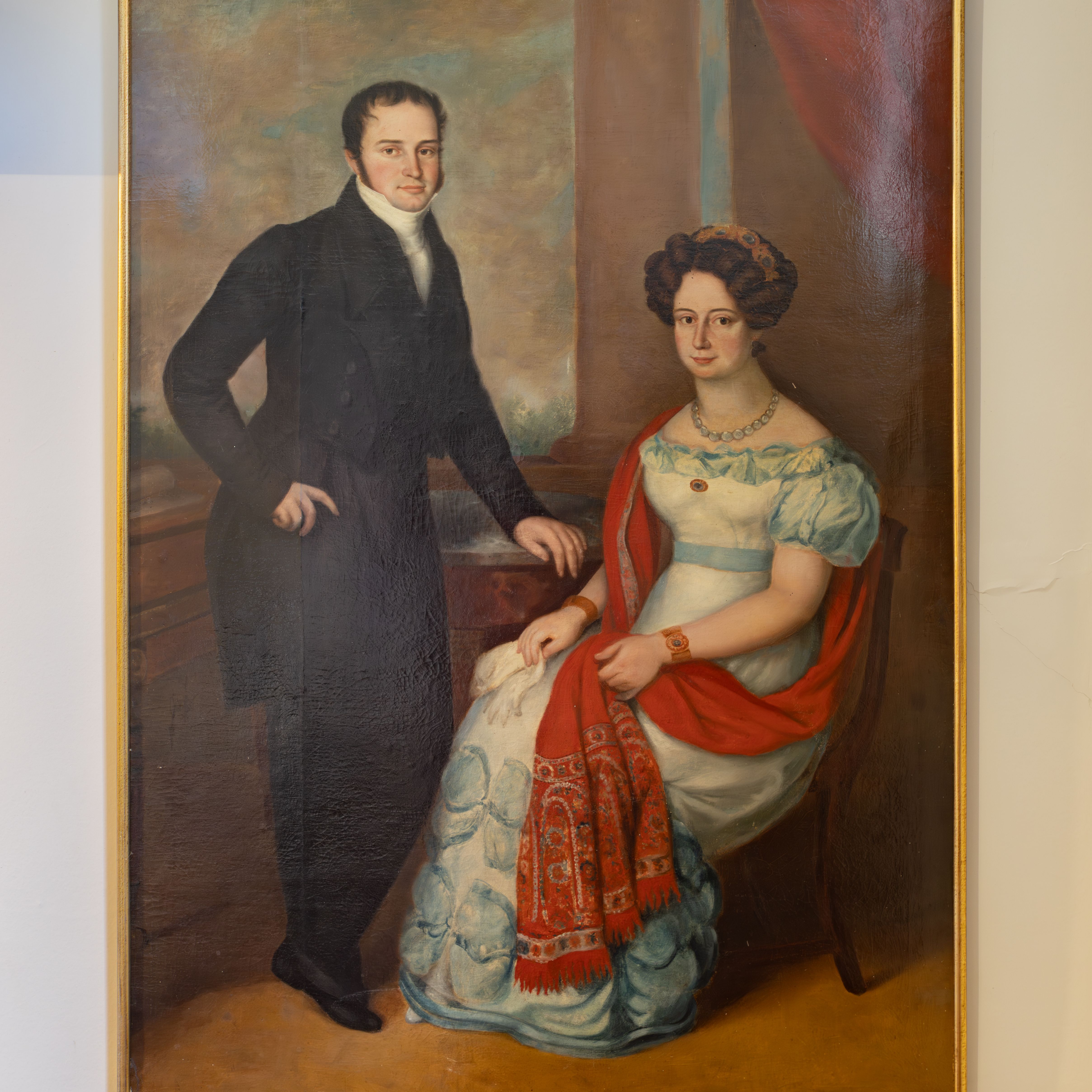 A classical portrait painting of a man standing beside a seated woman, both dressed in formal historical attire.