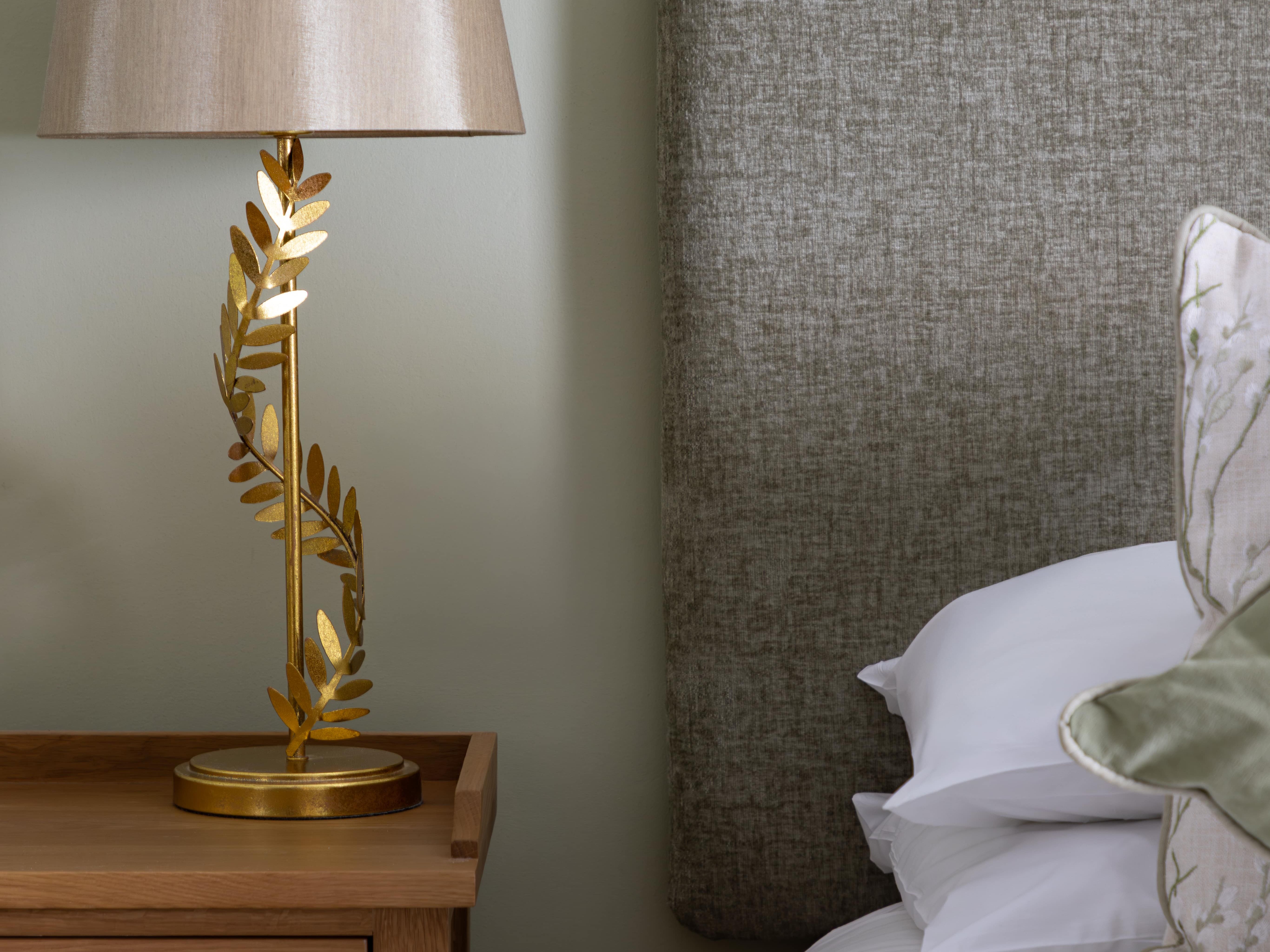 Nightstand with decorative lamp and bed with upholstered headboard