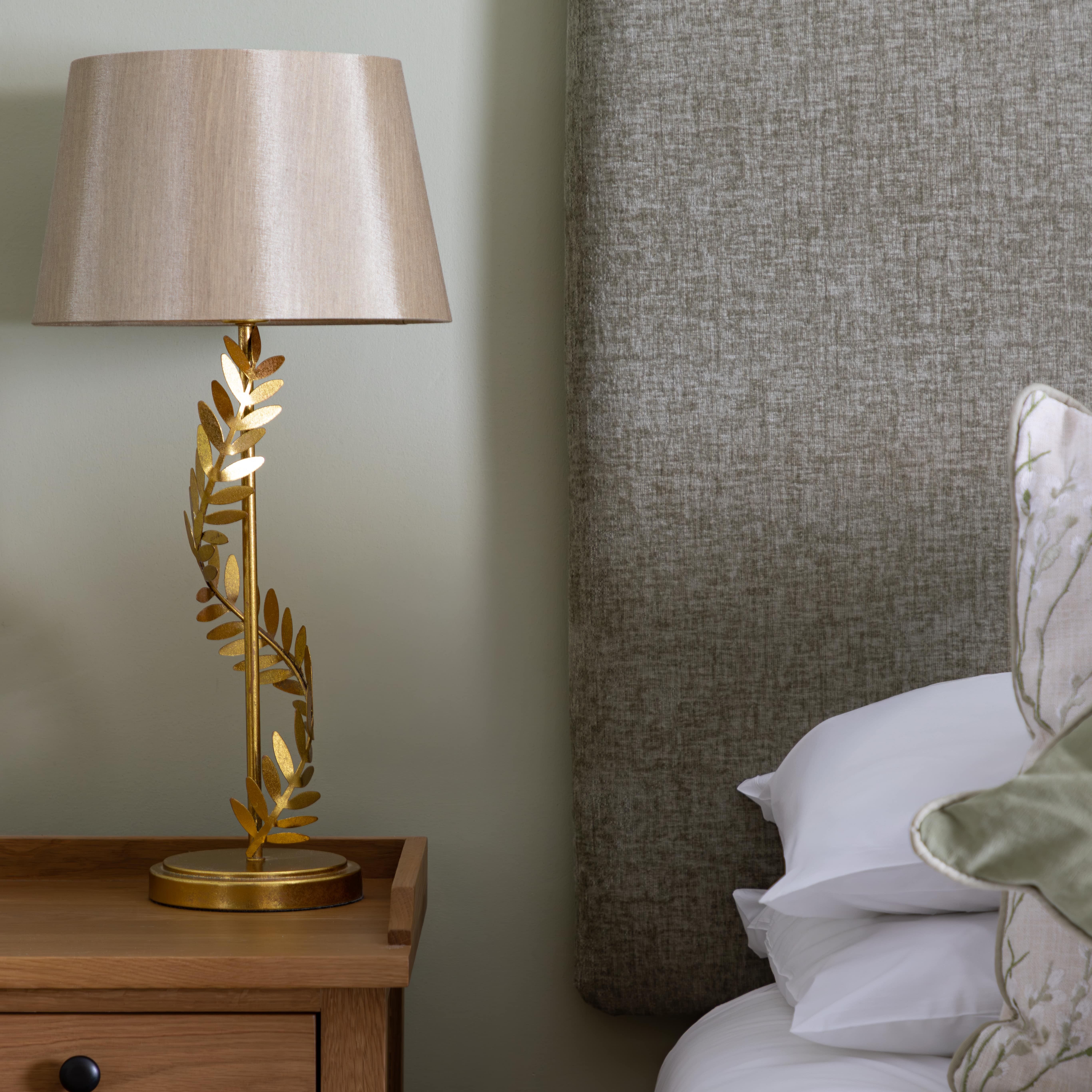 Nightstand with decorative lamp and bed with upholstered headboard