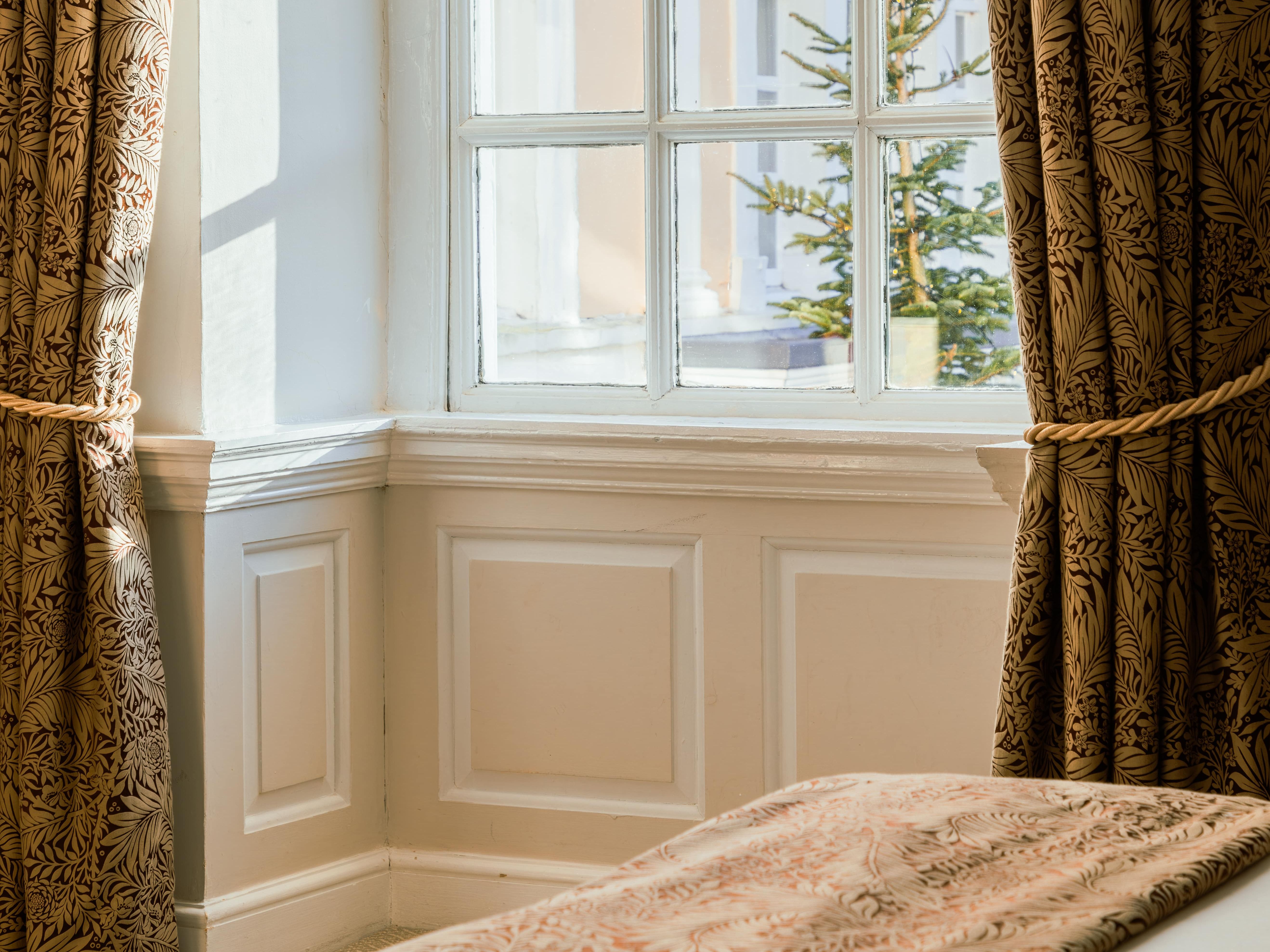 Sunlight streaming through a window with patterned curtains in a cozy room.