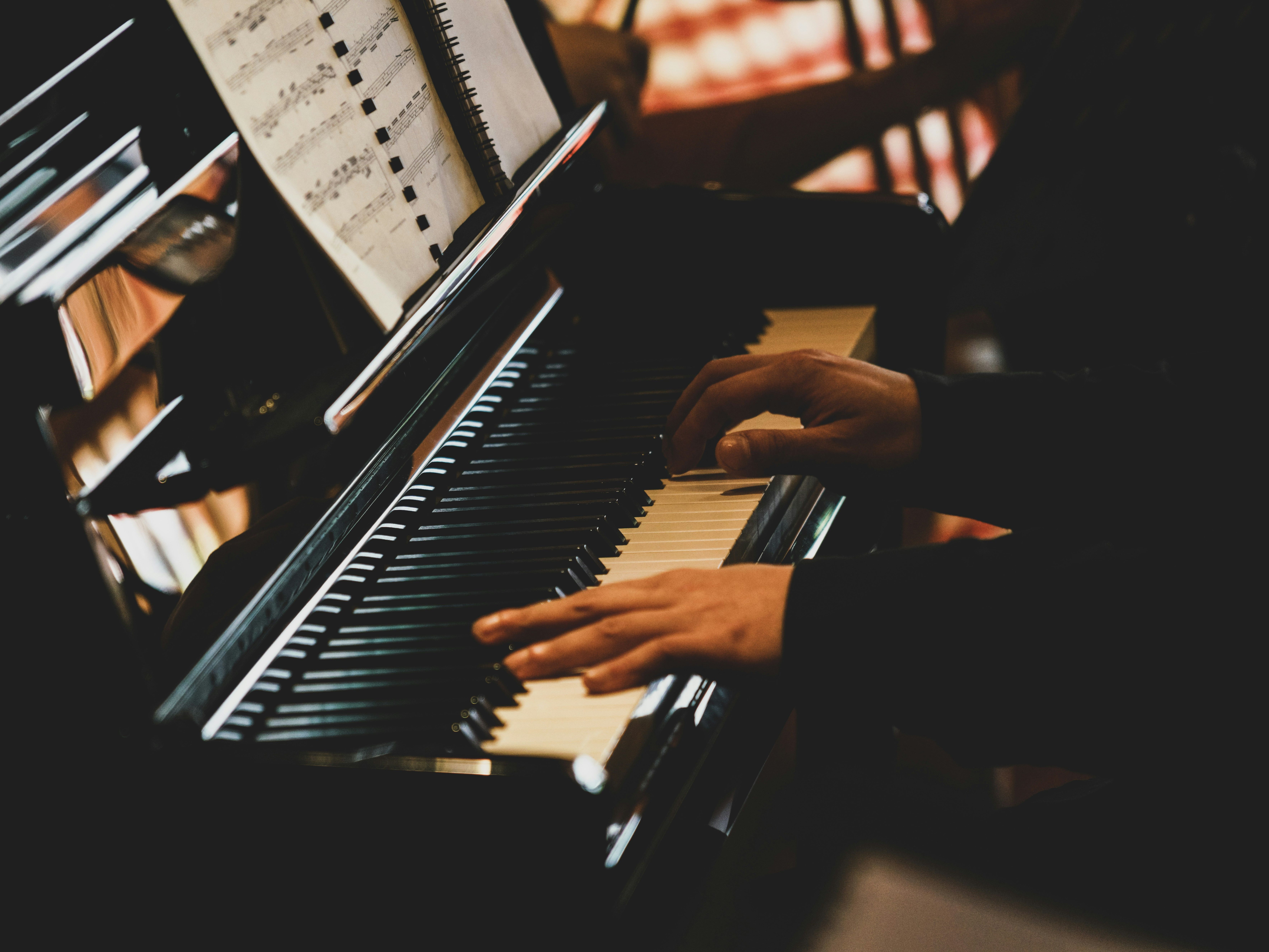 Hands playing a piano with sheet music visible
