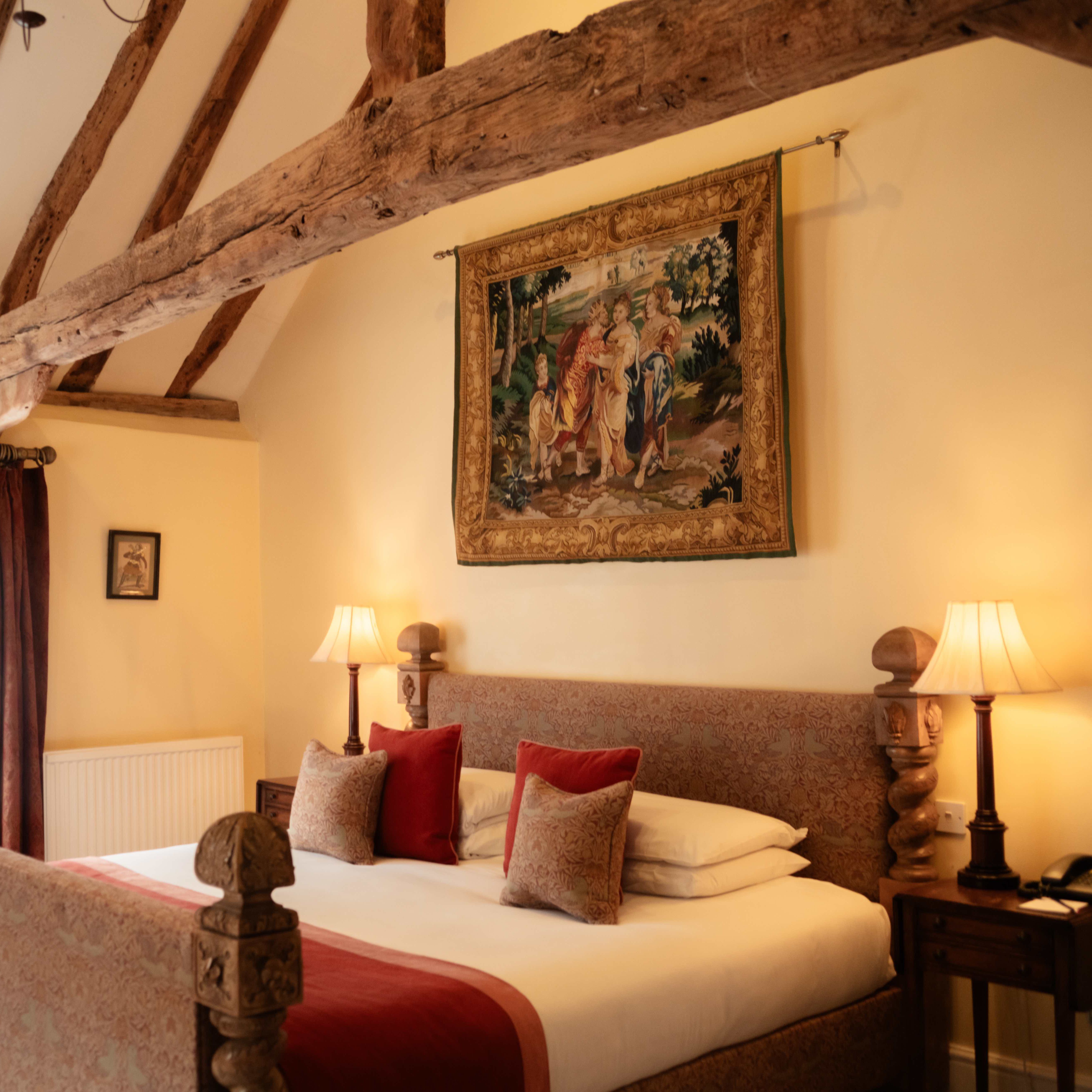 Cozy bedroom with exposed wooden beams, a large bed, and classic decor