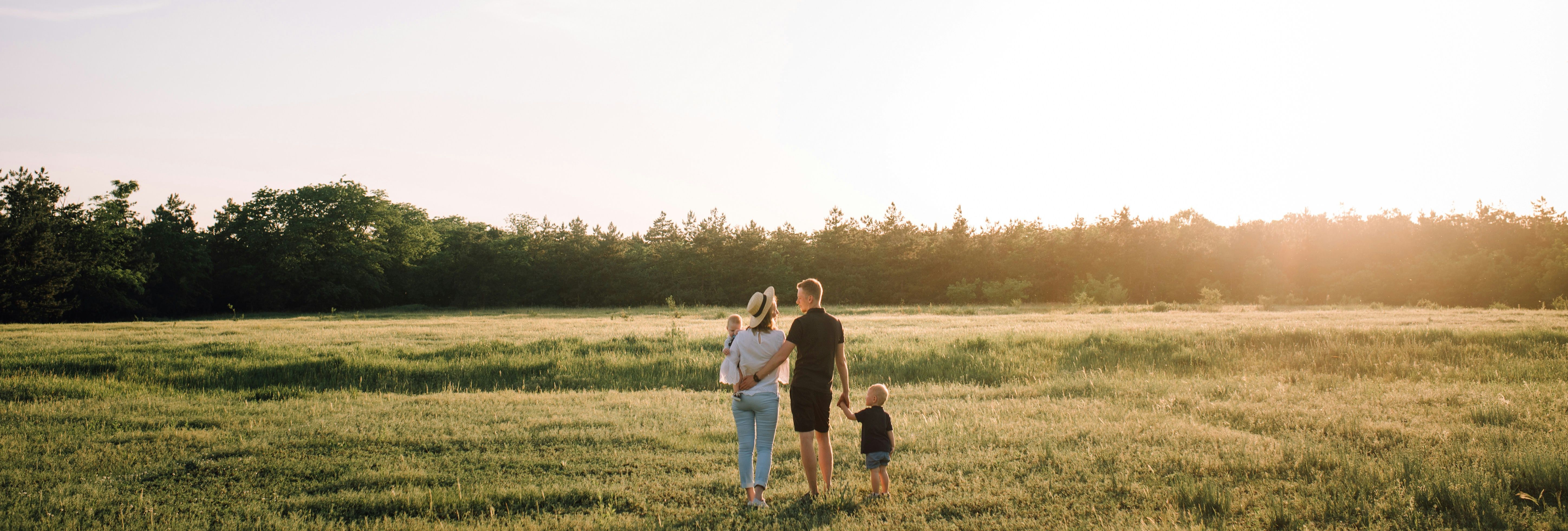 Family standing together in a field at sunset