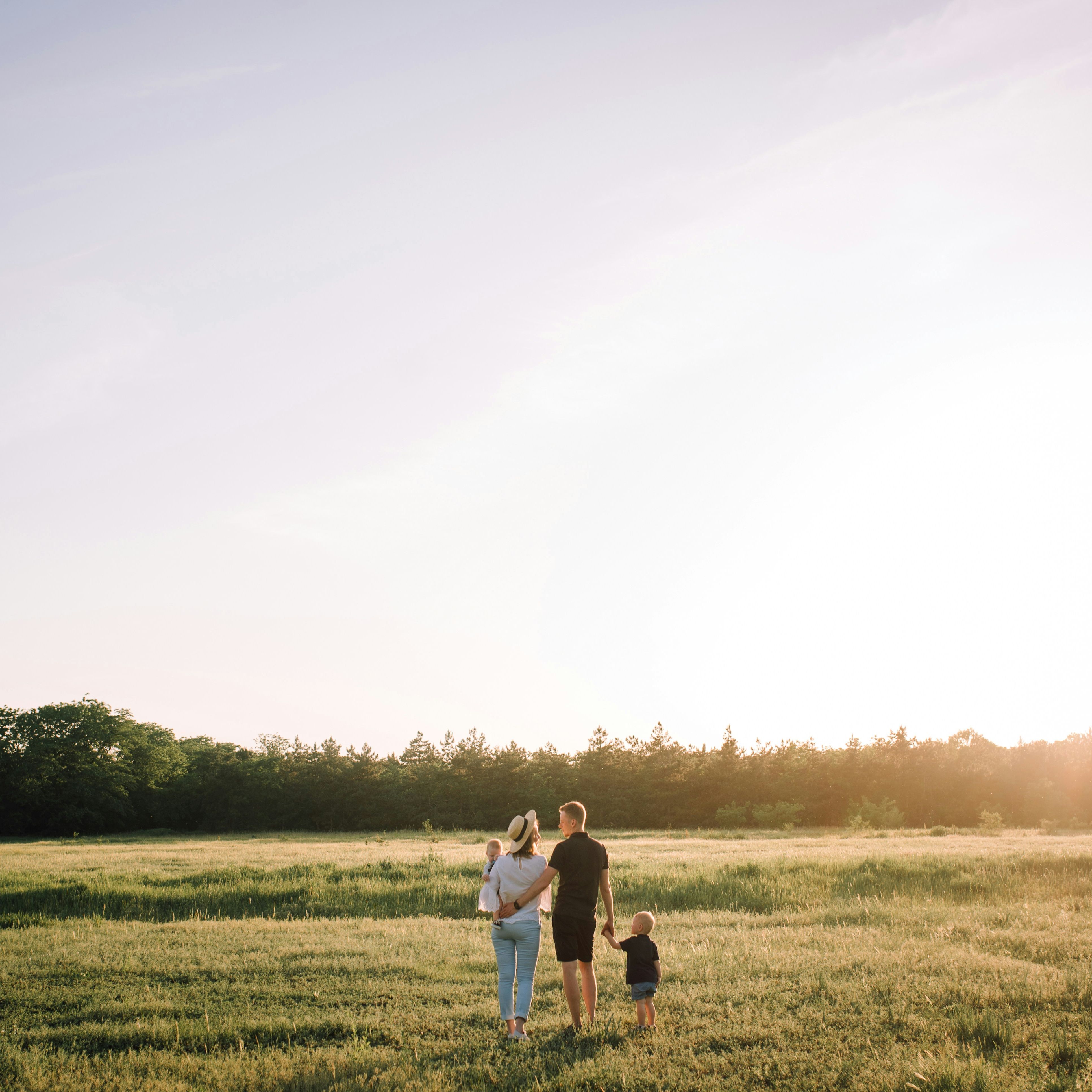 Family standing together in a field at sunset
