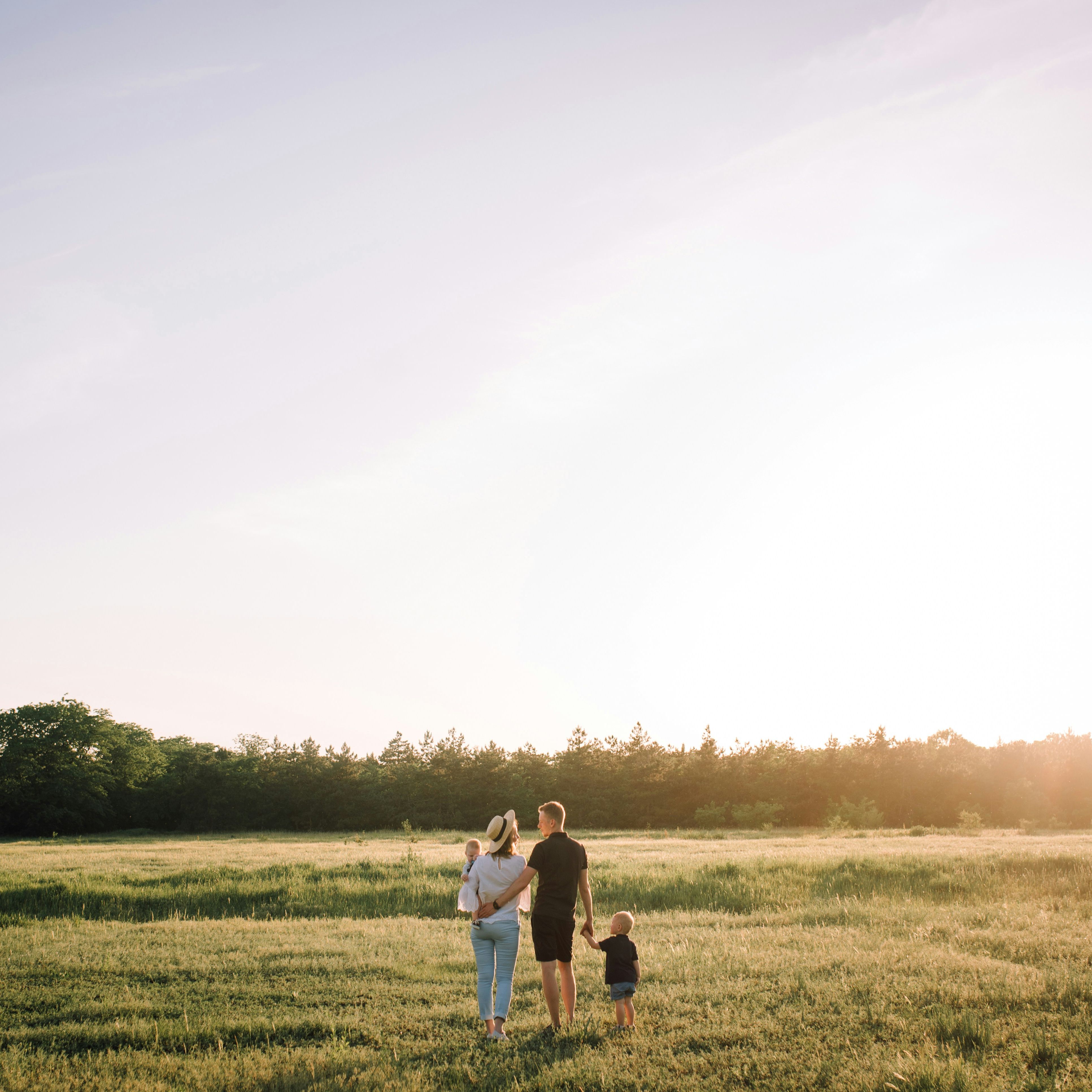 Family standing together in a field at sunset