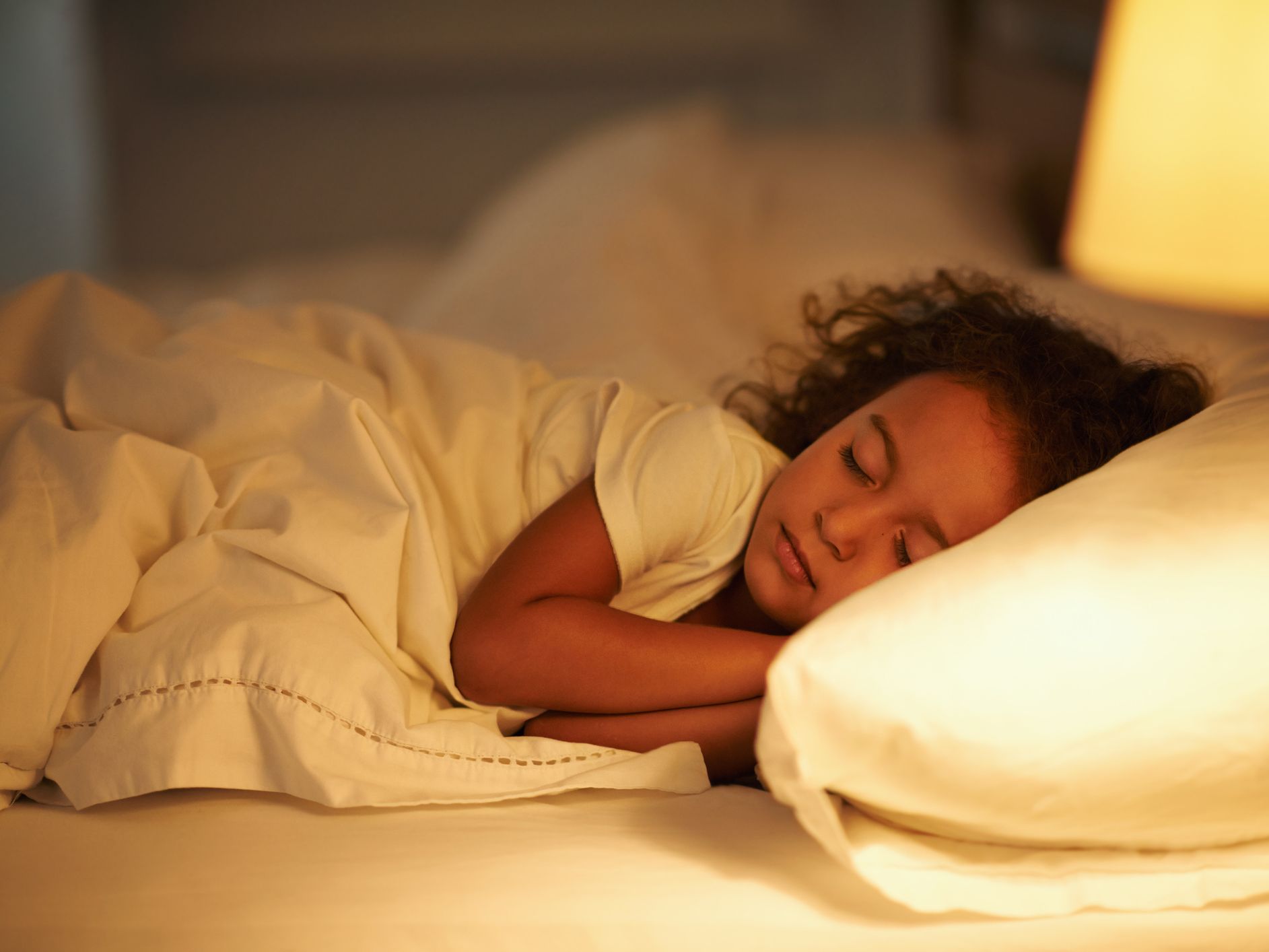 Child sleeping peacefully in bed with soft lighting