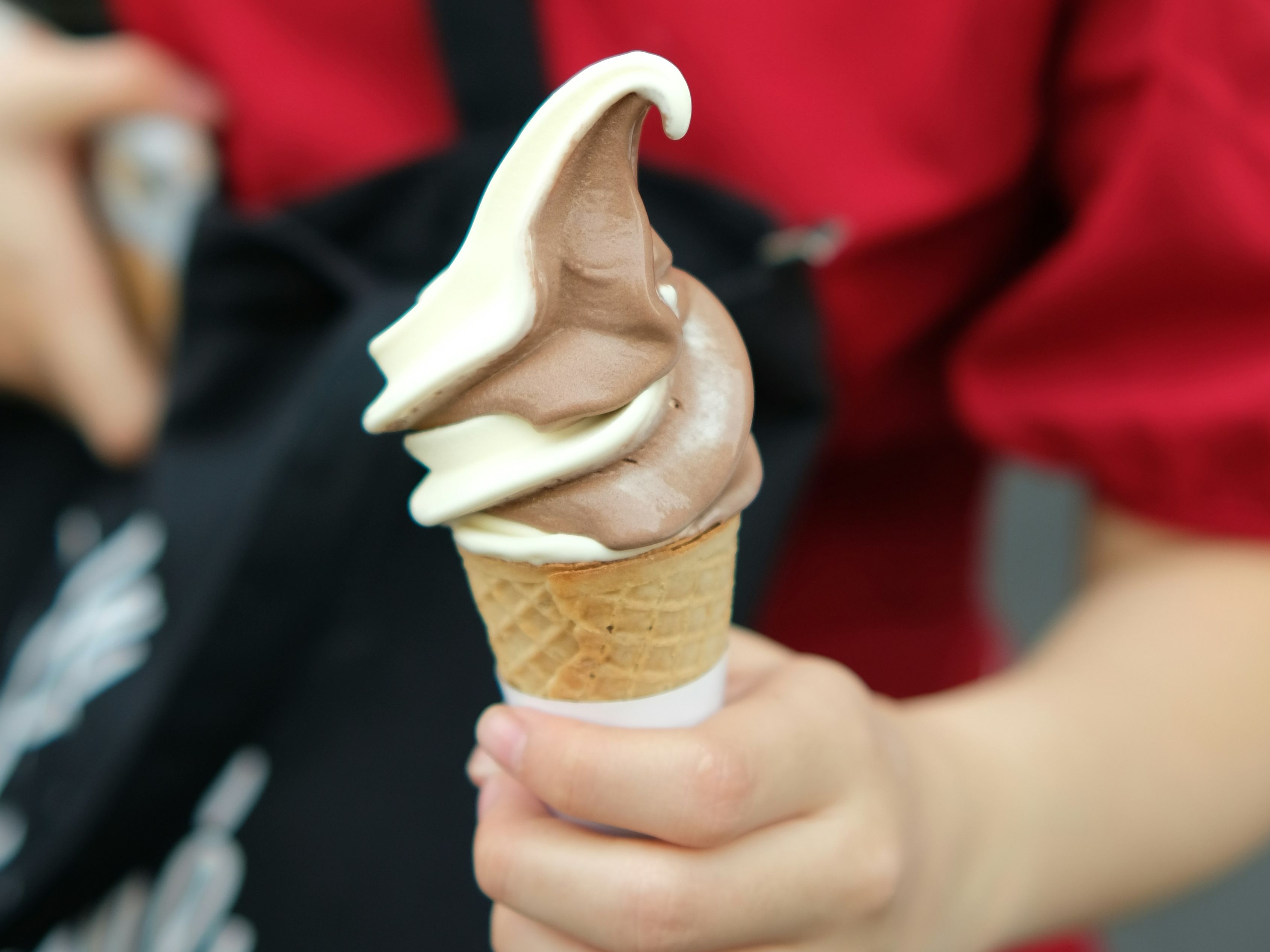Person holding a swirl soft serve ice cream cone