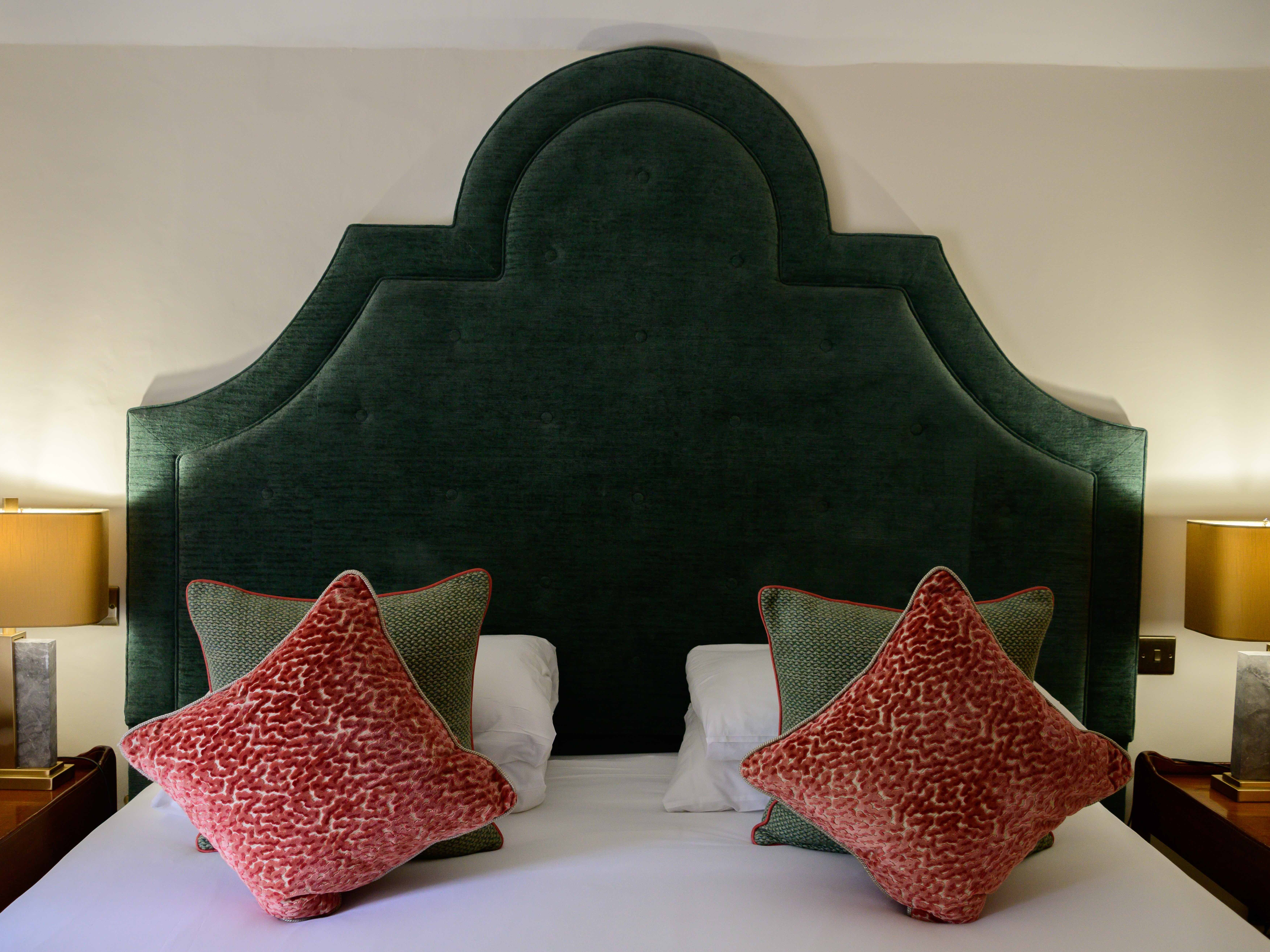 Bed with large upholstered headboard, two bedside lamps, and decorative pillows
