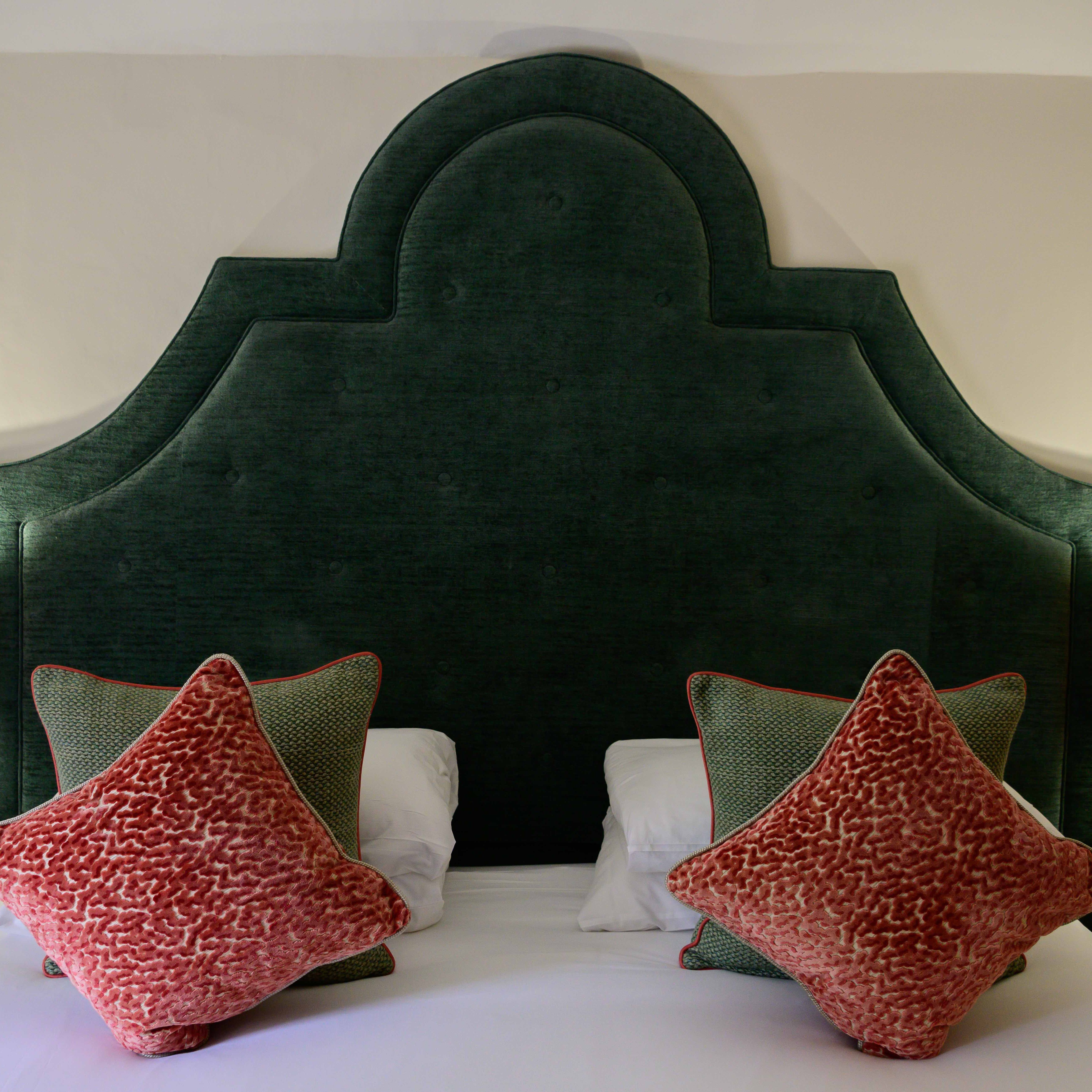 Bed with large upholstered headboard, two bedside lamps, and decorative pillows