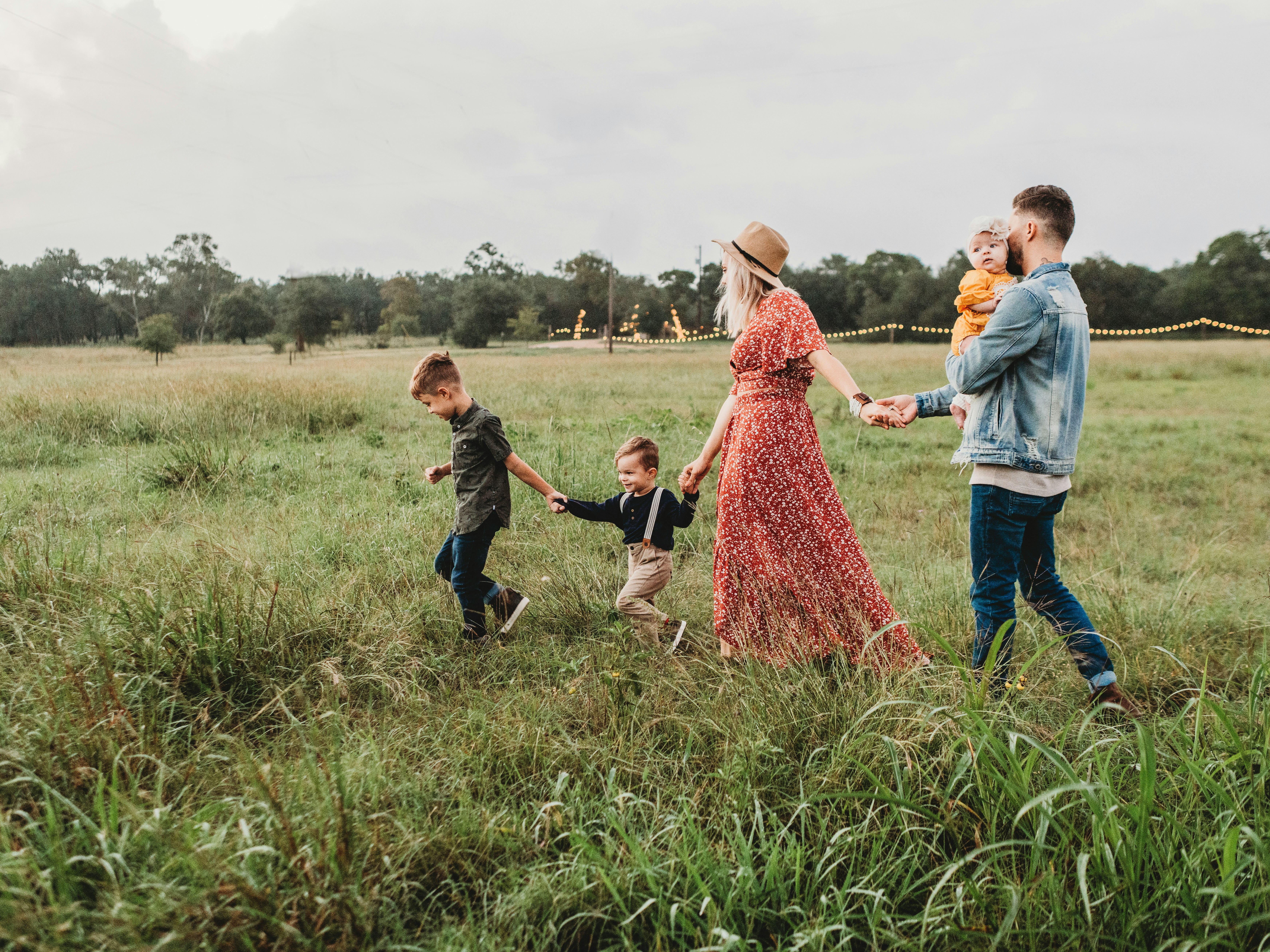 Family walking together in a grassy field at sunset.