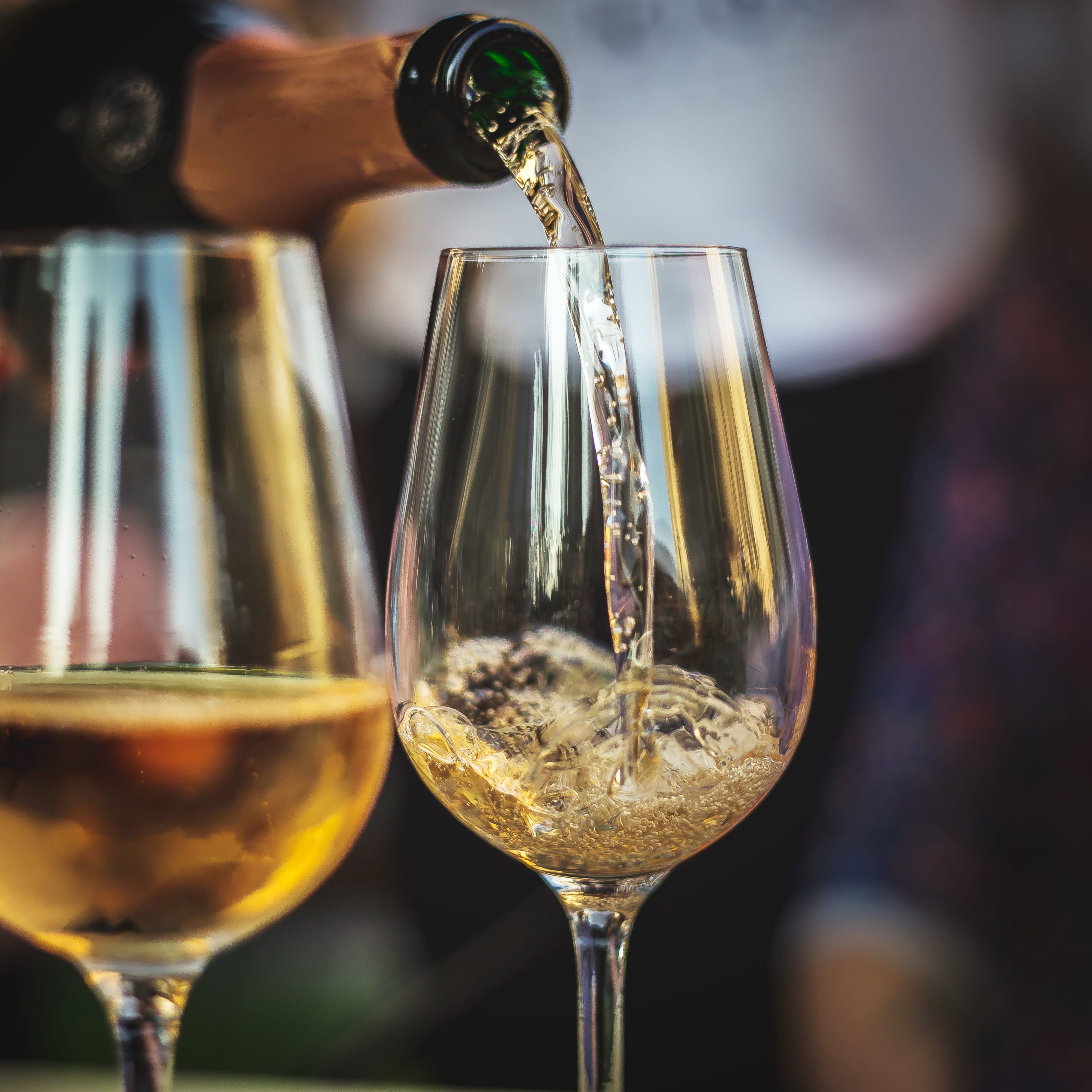 Champagne being poured into a wine glass with another filled glass beside it