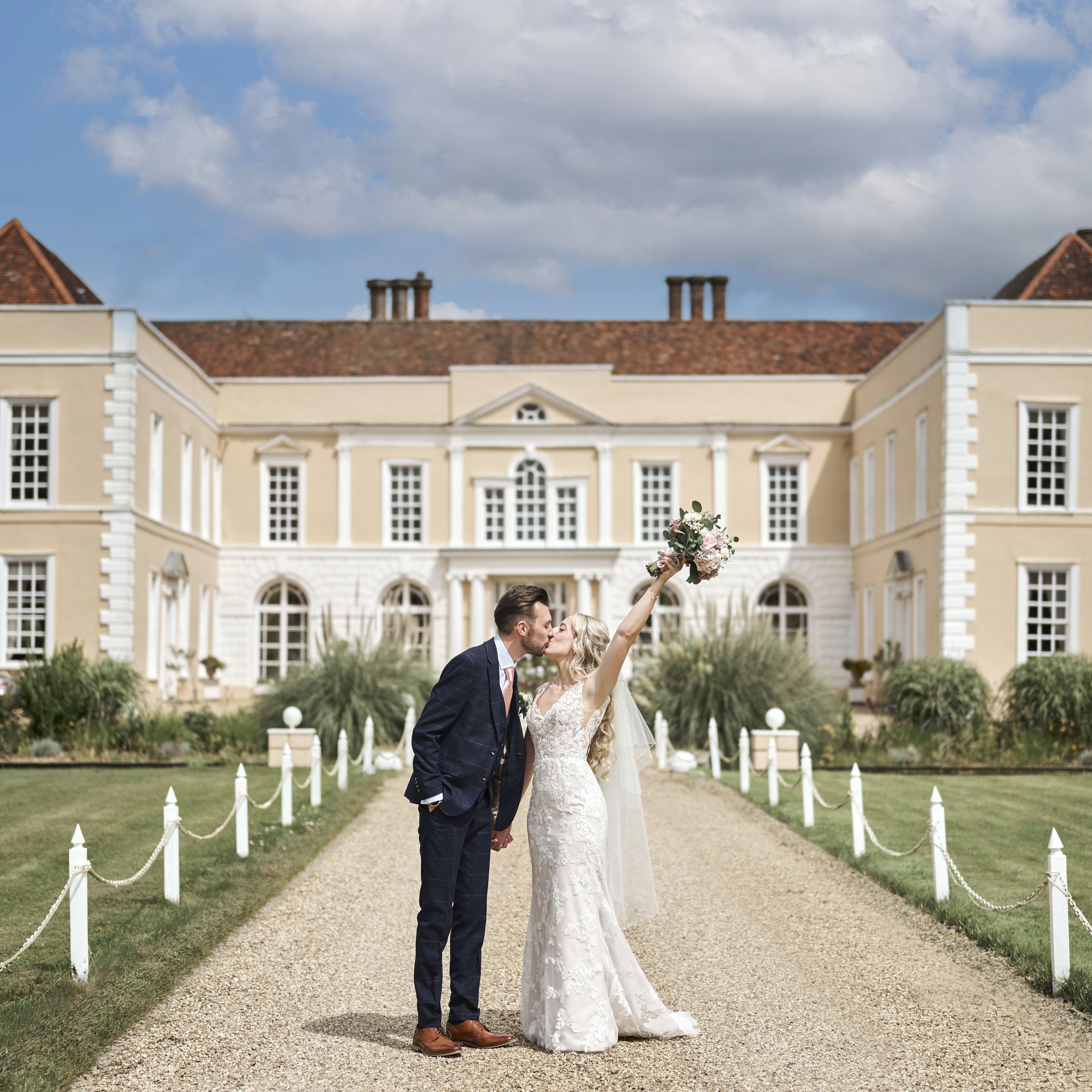Bride and groom kissing outside Hintlesham Hall wedding venue in Ipswich on a sunny day.