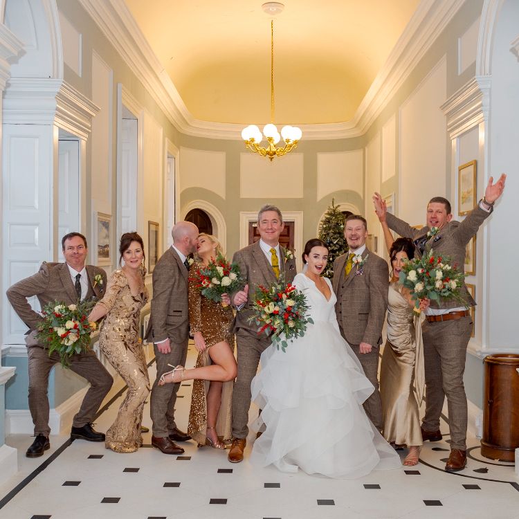 Bride and wedding party posing playfully in an elegant hallway