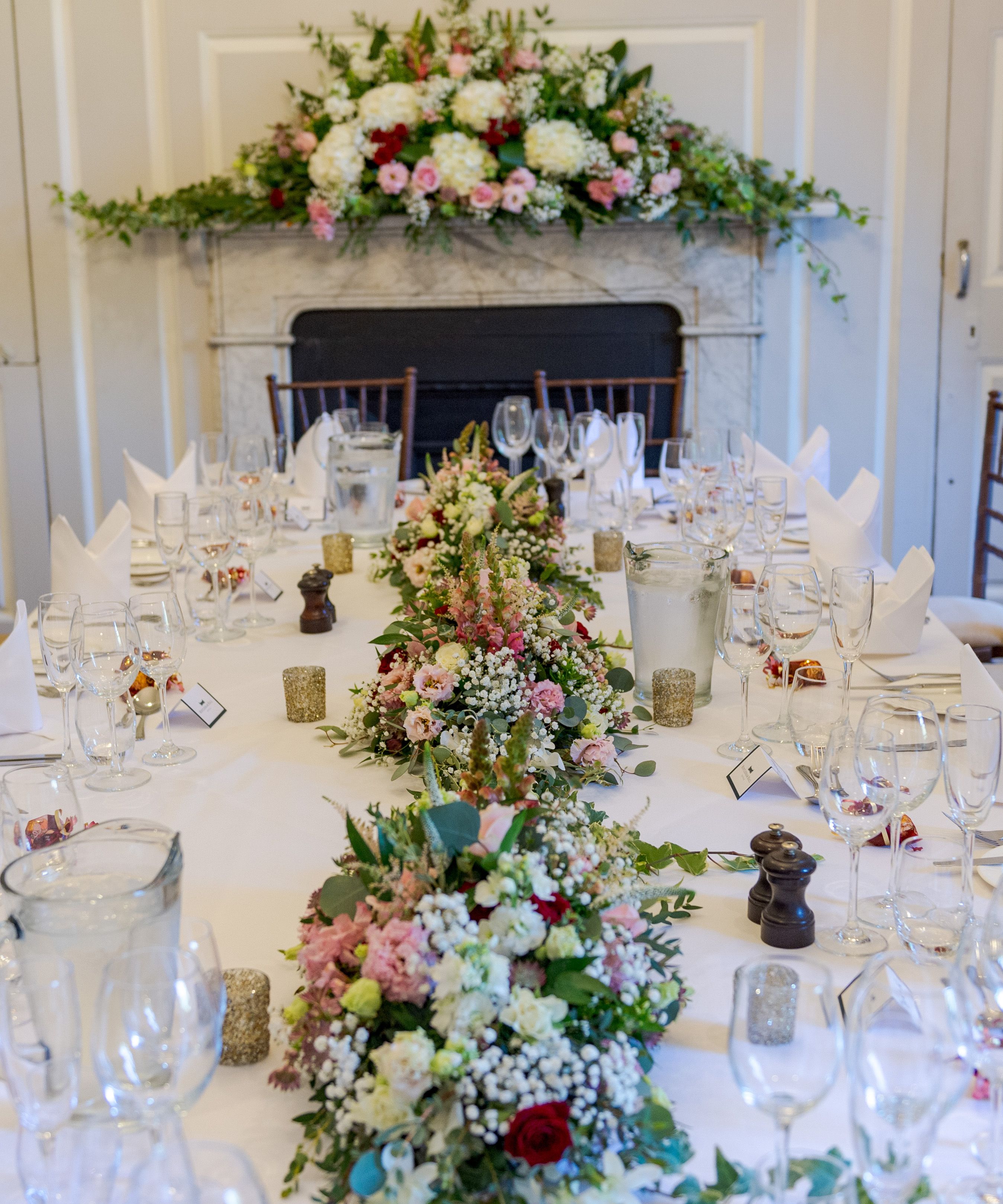 Elegant banquet table set with white linen, folded napkins and floral centrepieces in a formal dining room