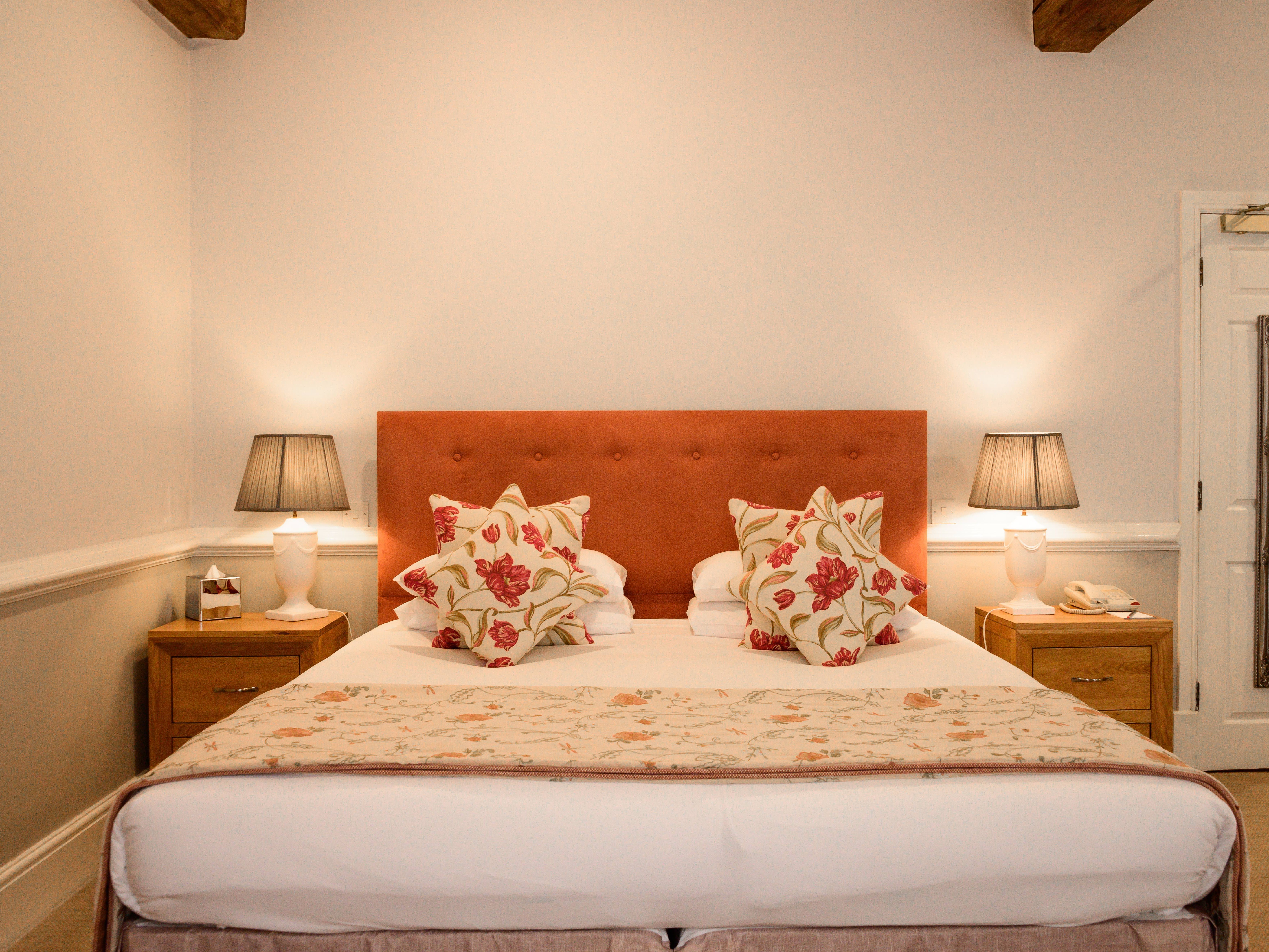 Cozy bedroom with a double bed, floral pillows, bedside tables, and lamps