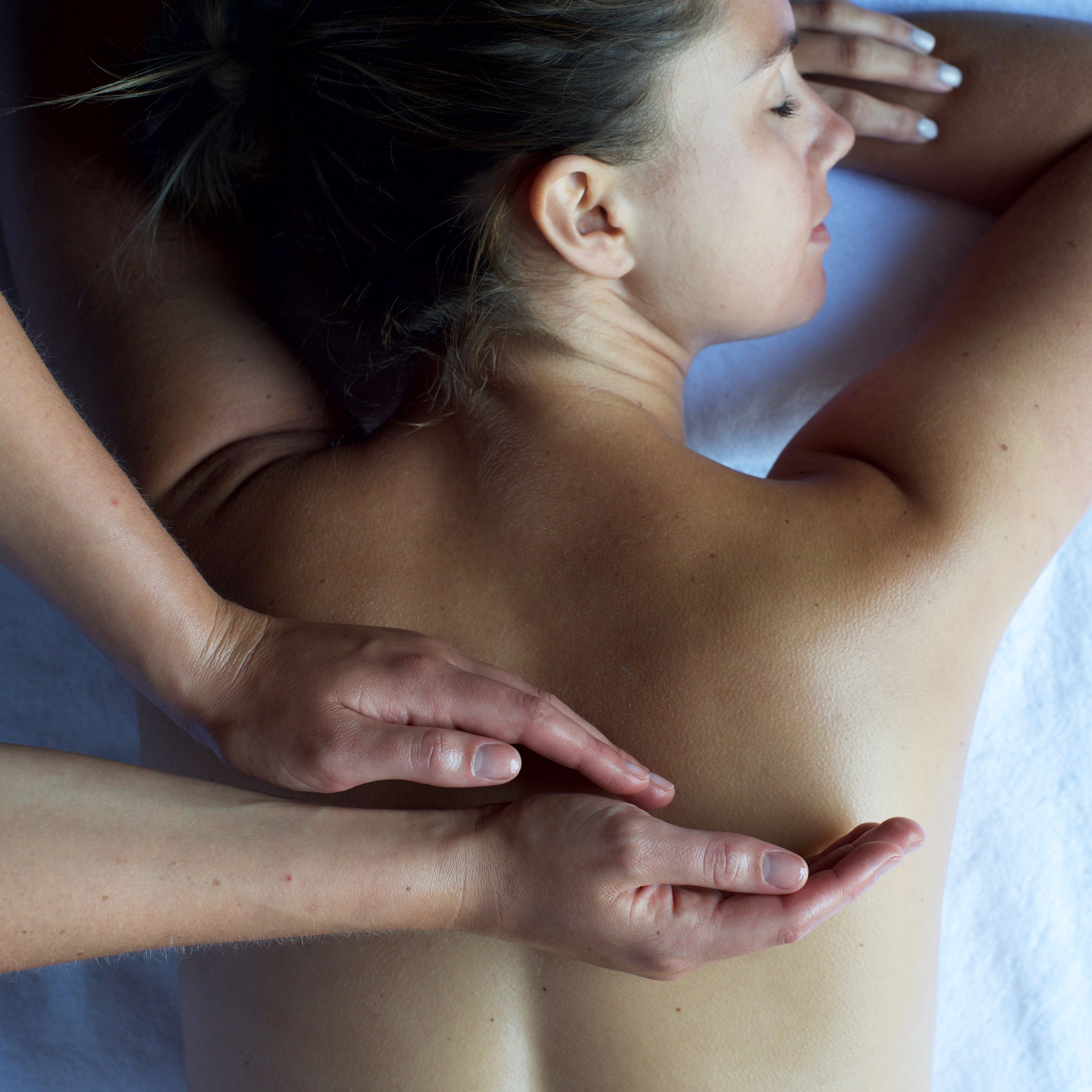 Person receiving a back massage while lying face down on a massage table