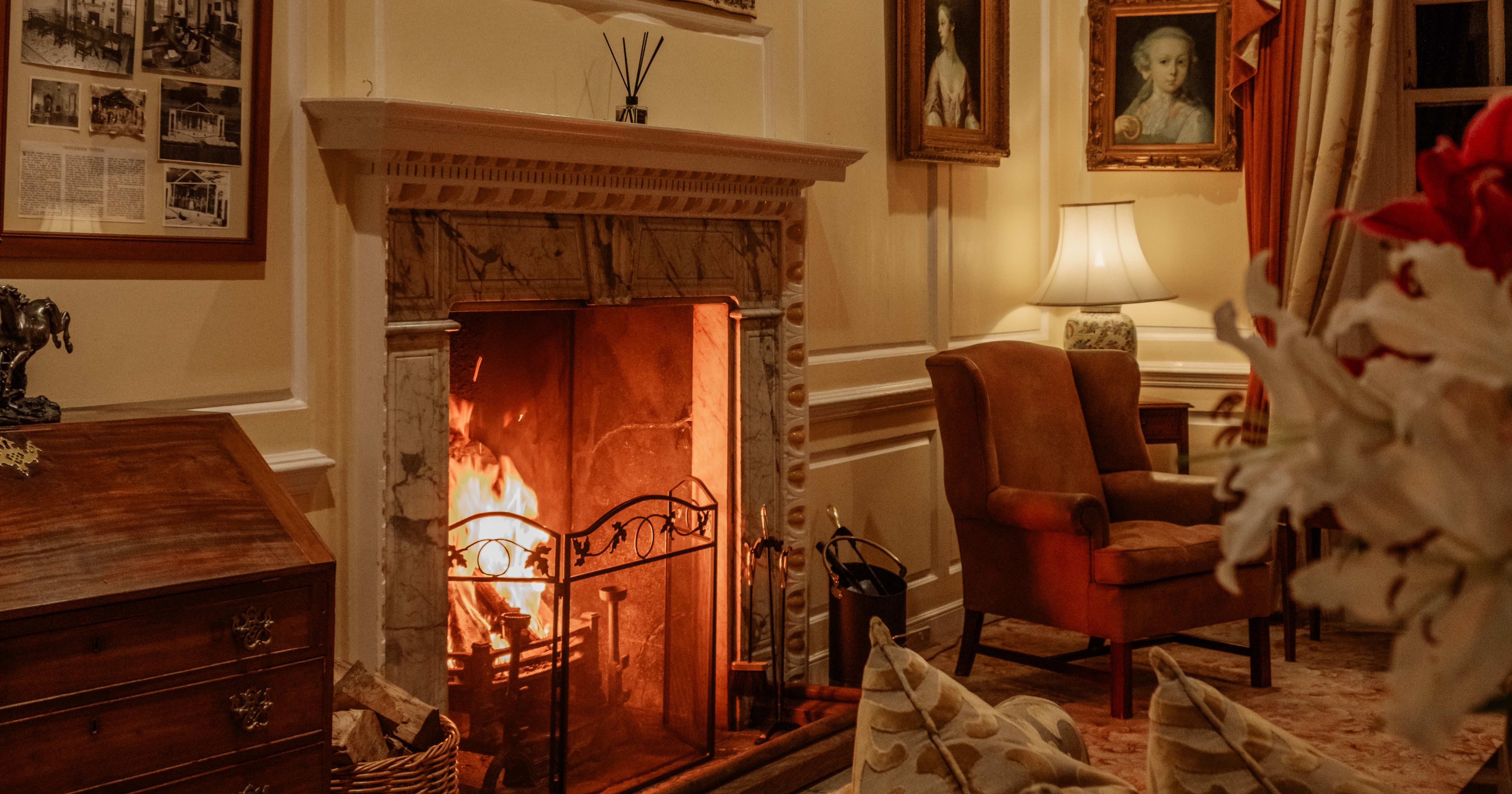 Elegant living room with a lit fireplace, classical furniture, and artwork on the walls