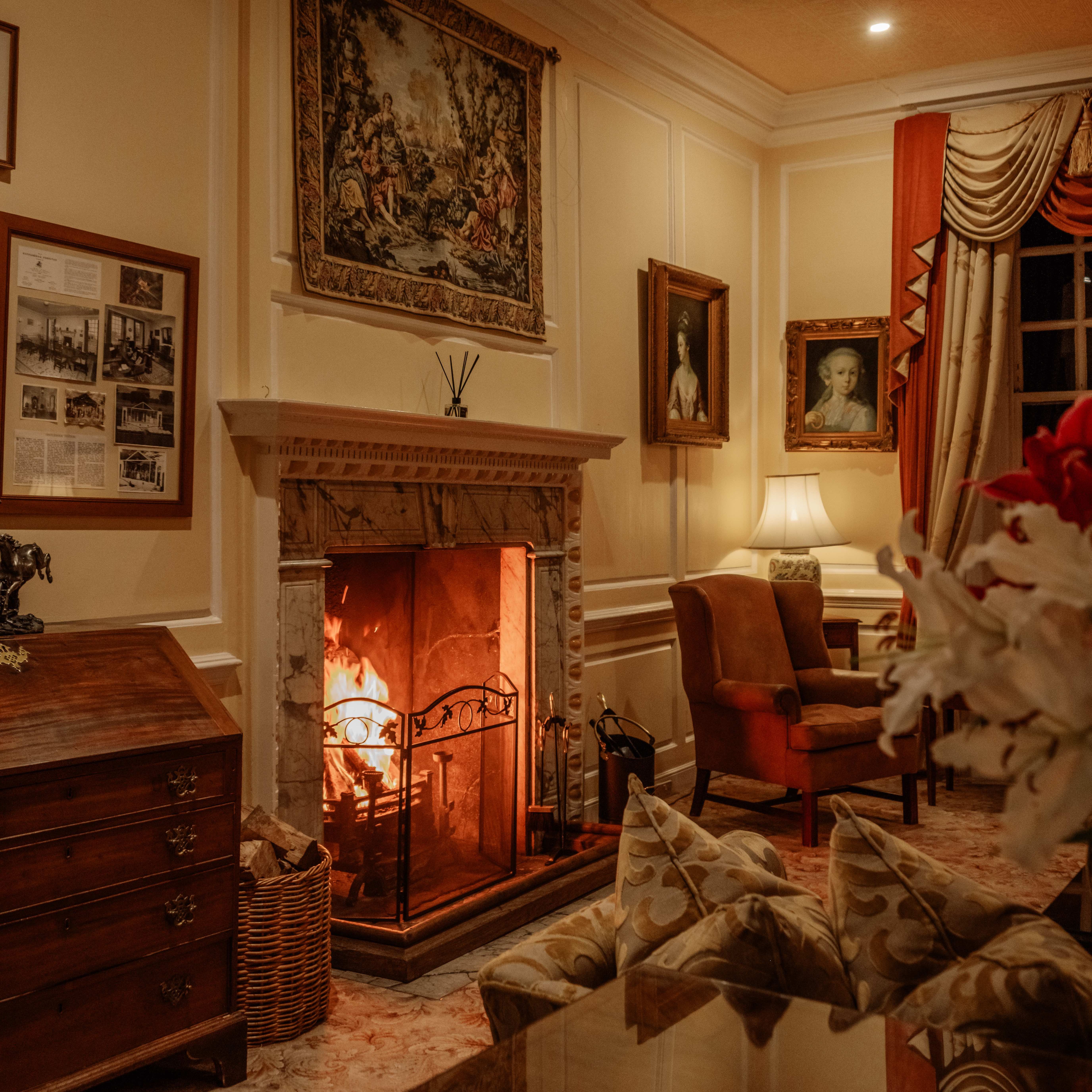 Elegant living room with a lit fireplace, classical furniture, and artwork on the walls