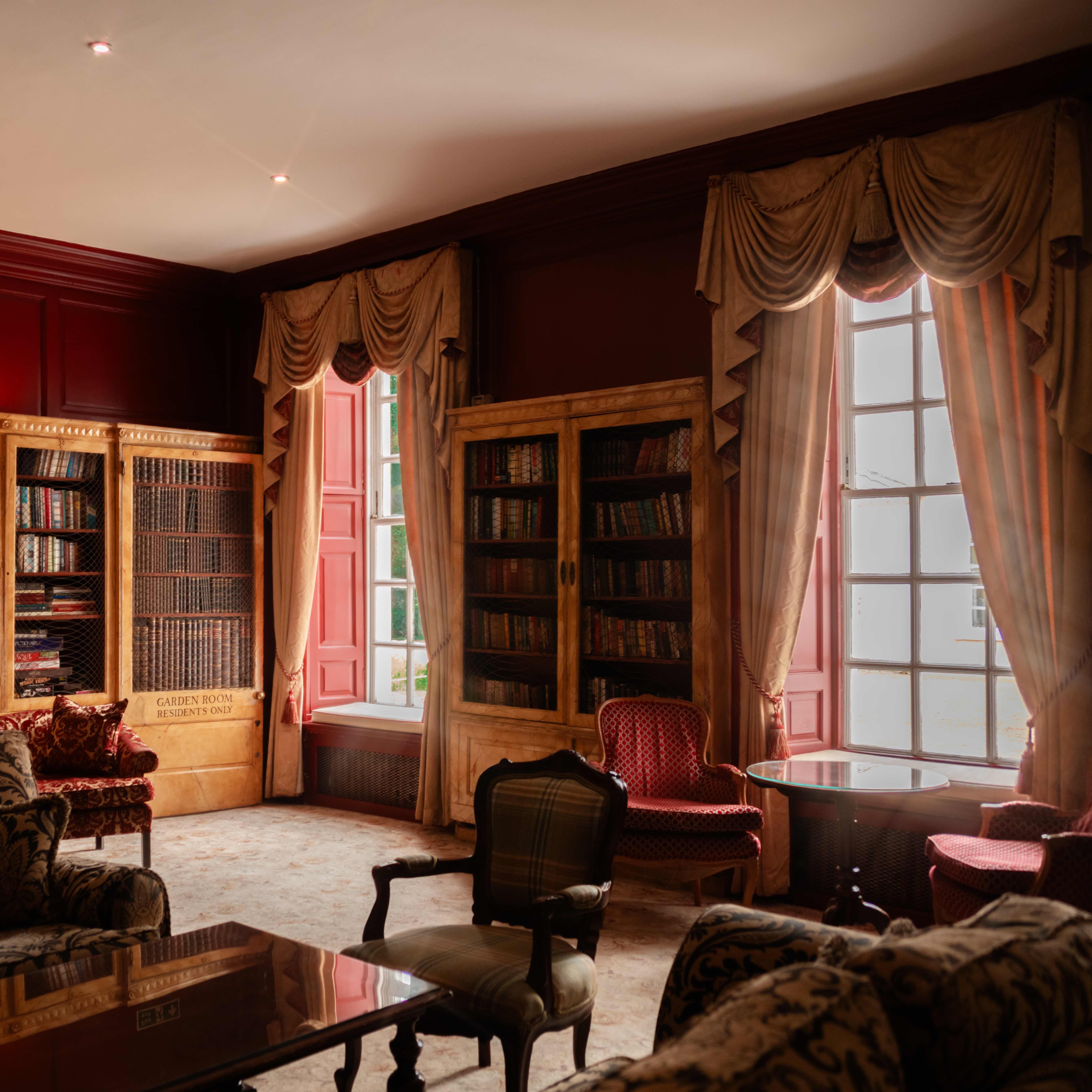 Elegant library room with vintage furniture, large bookcases, and tall curtained windows