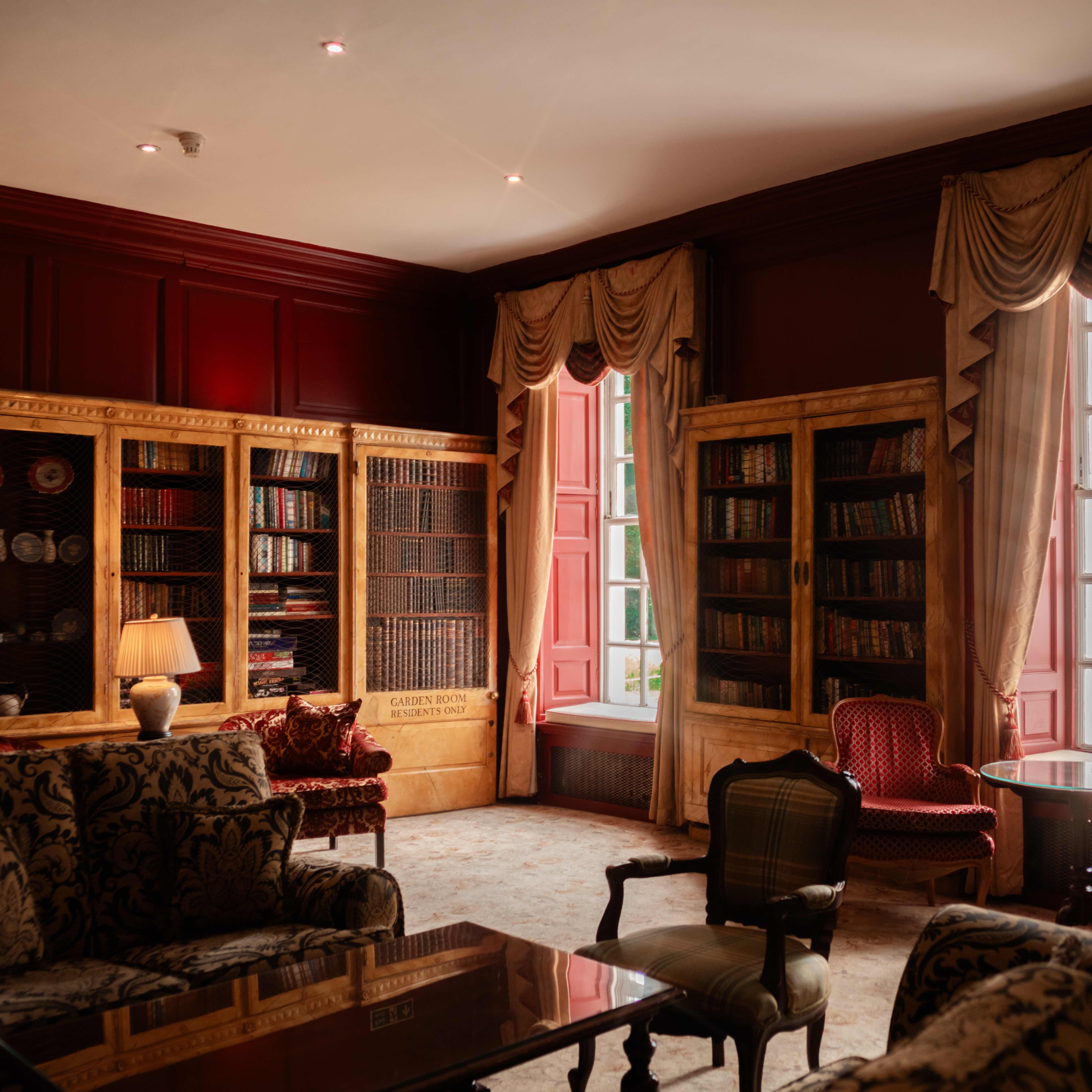 Elegant library room with vintage furniture, large bookcases, and tall curtained windows
