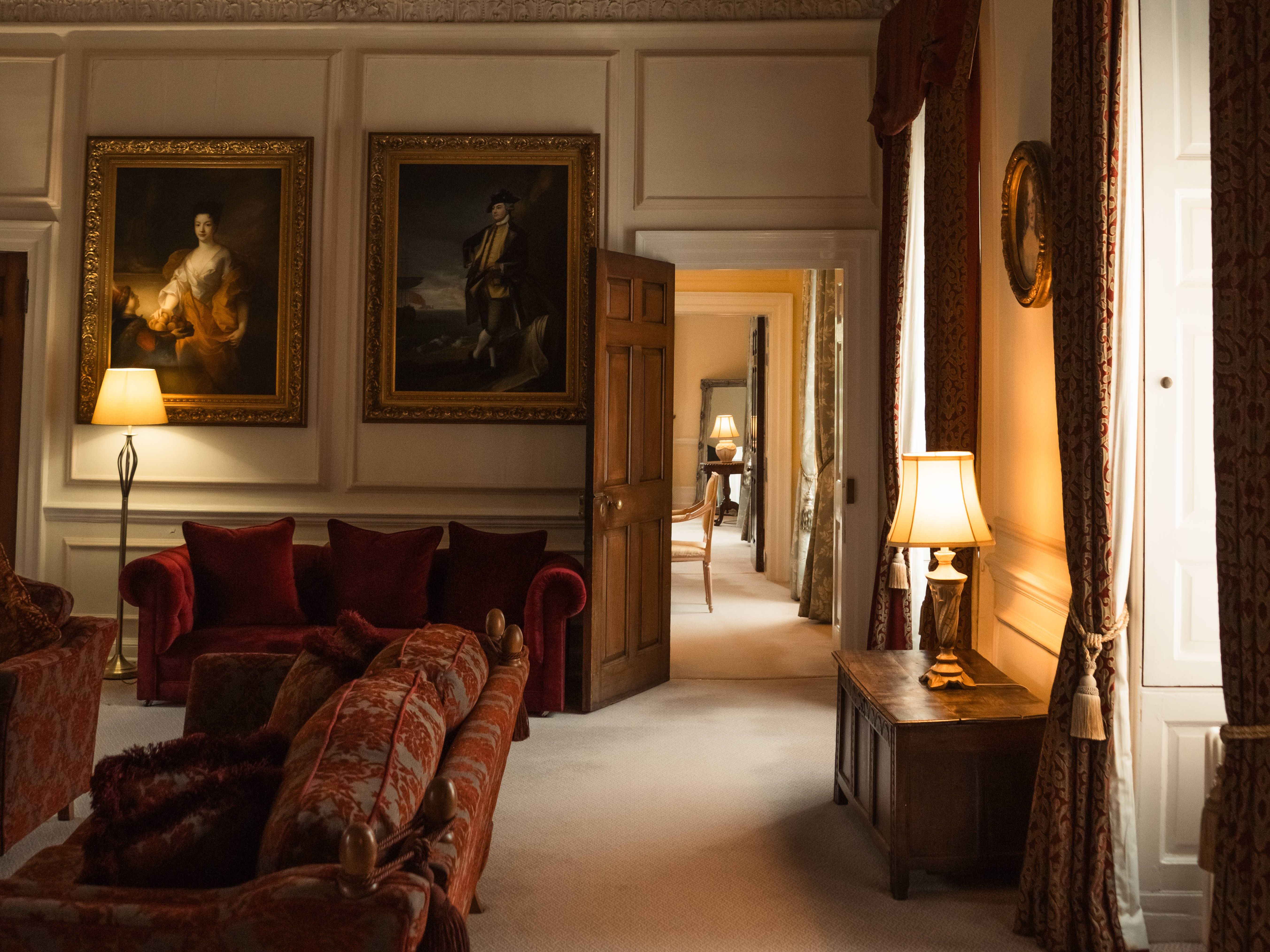 Elegant historical living room with ornate ceiling, vintage furniture, and classical paintings.