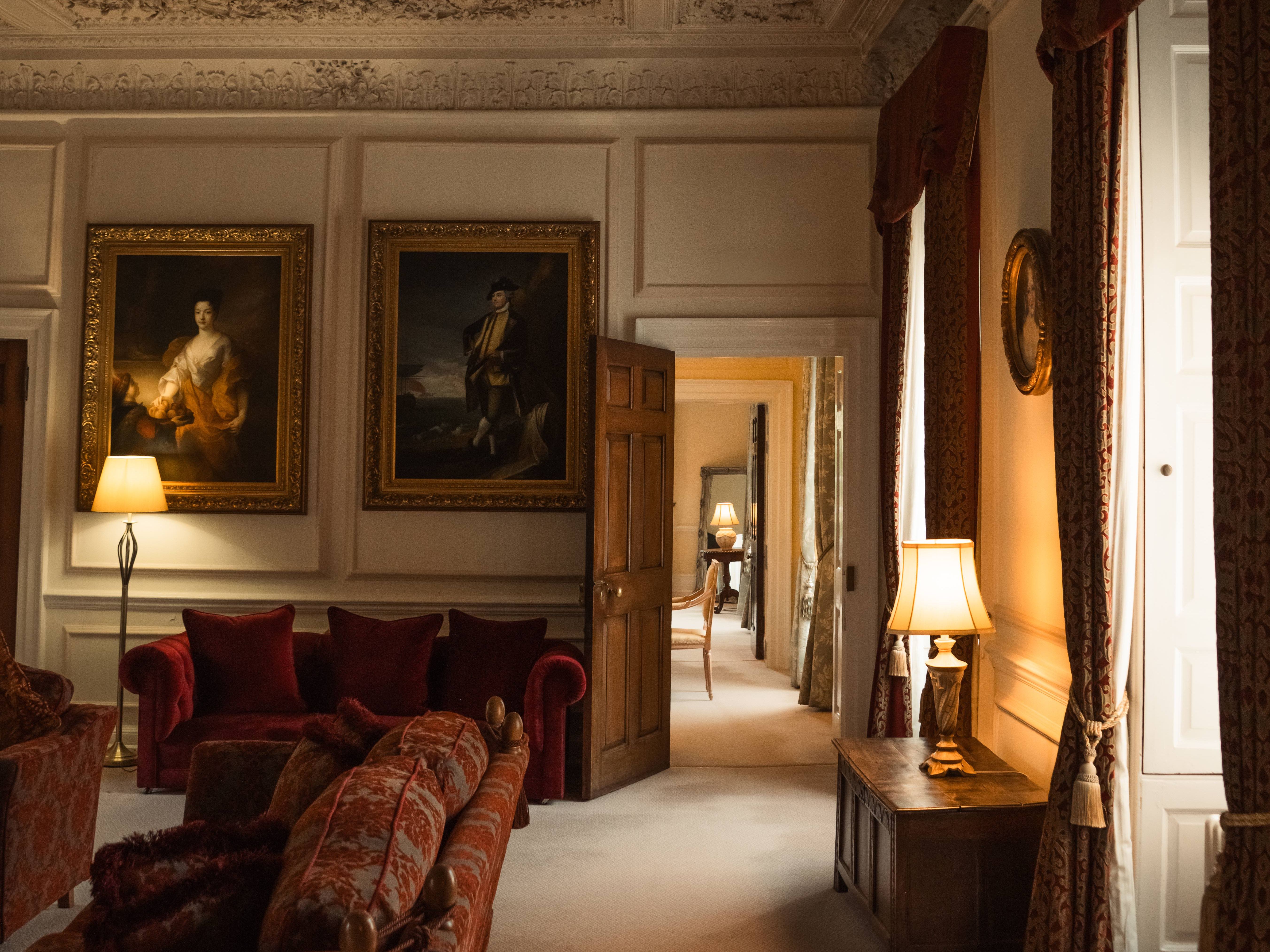 Elegant historical living room with ornate ceiling, vintage furniture, and classical paintings.