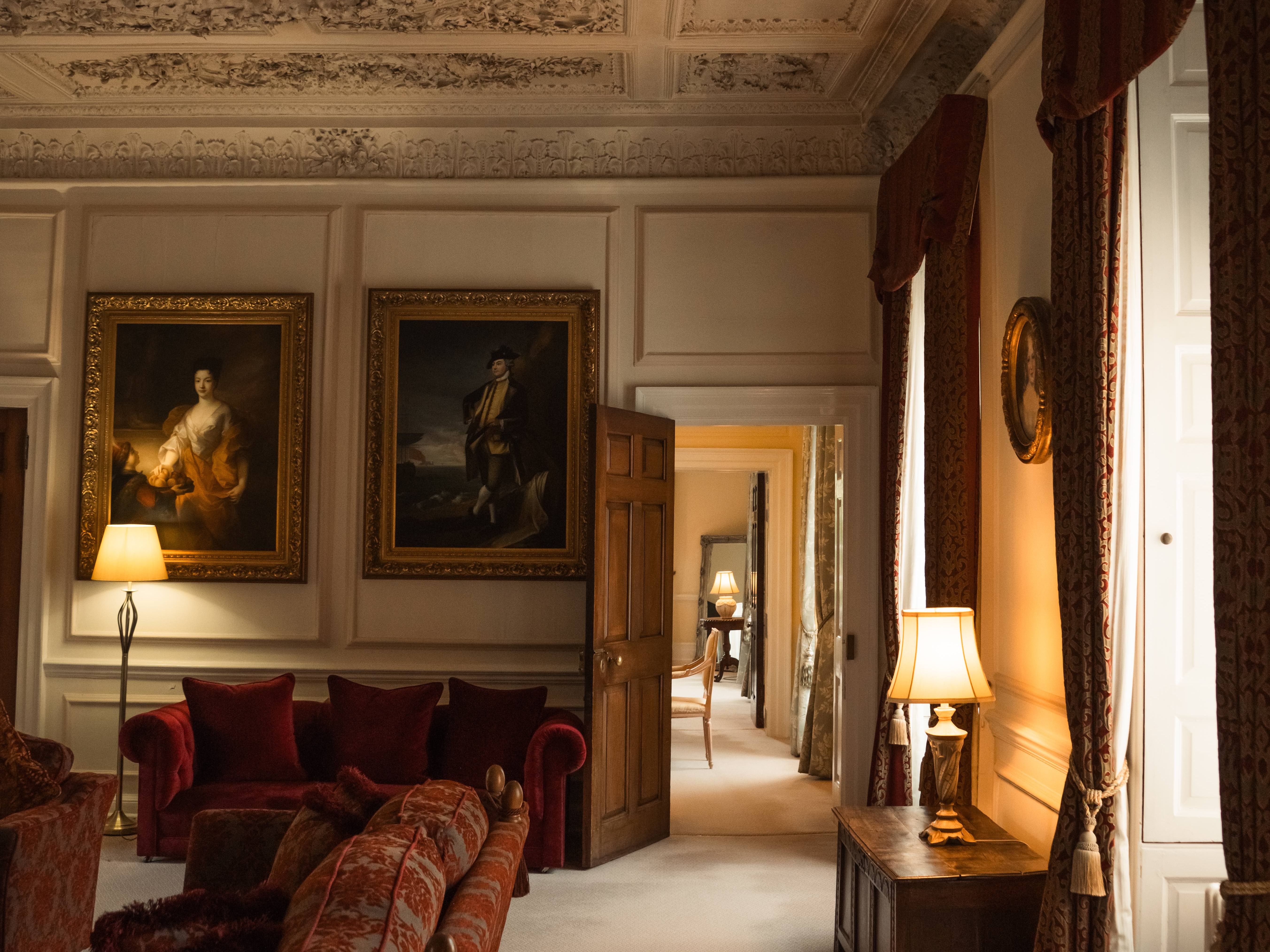 Elegant historical living room with ornate ceiling, vintage furniture, and classical paintings.