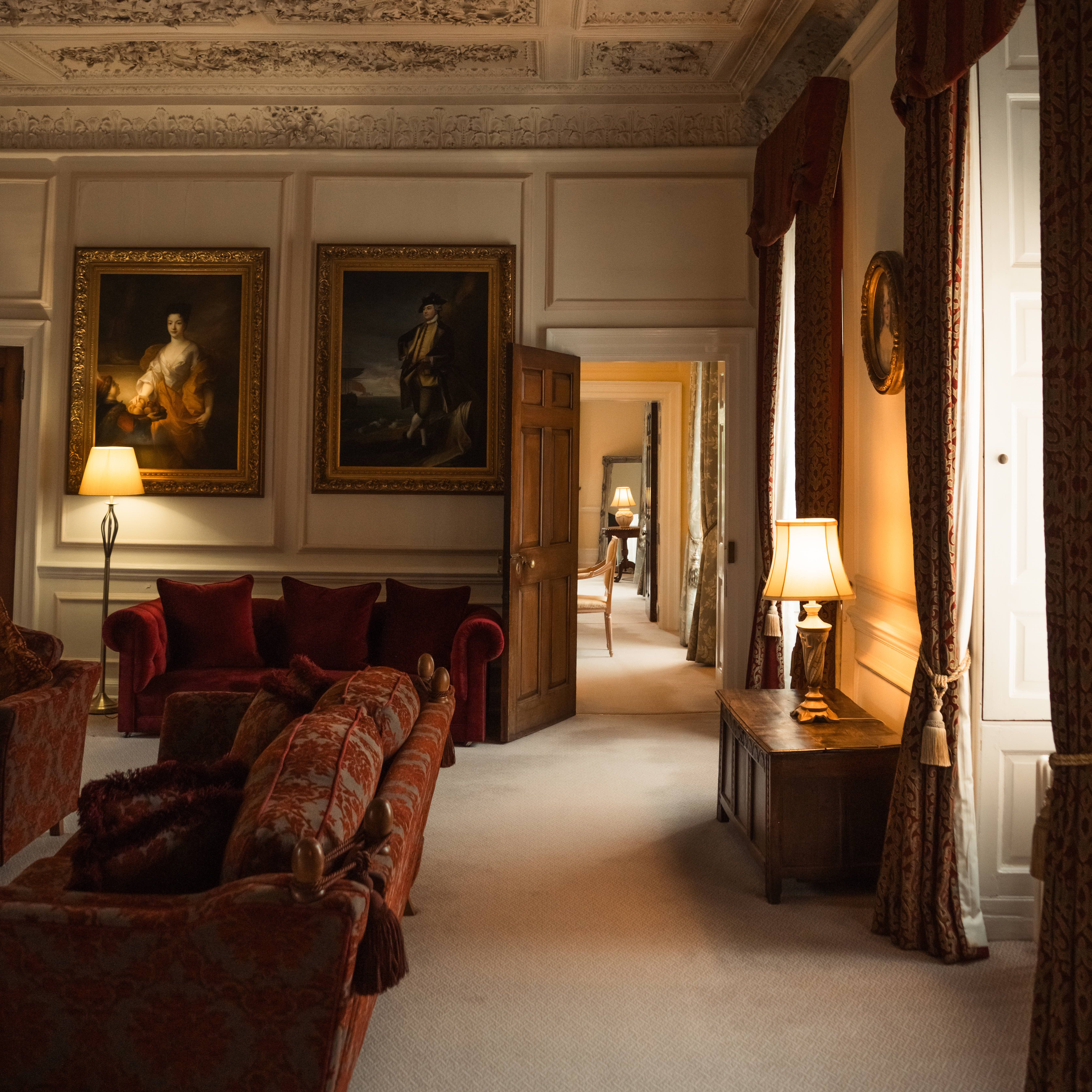 Elegant historical living room with ornate ceiling, vintage furniture, and classical paintings.
