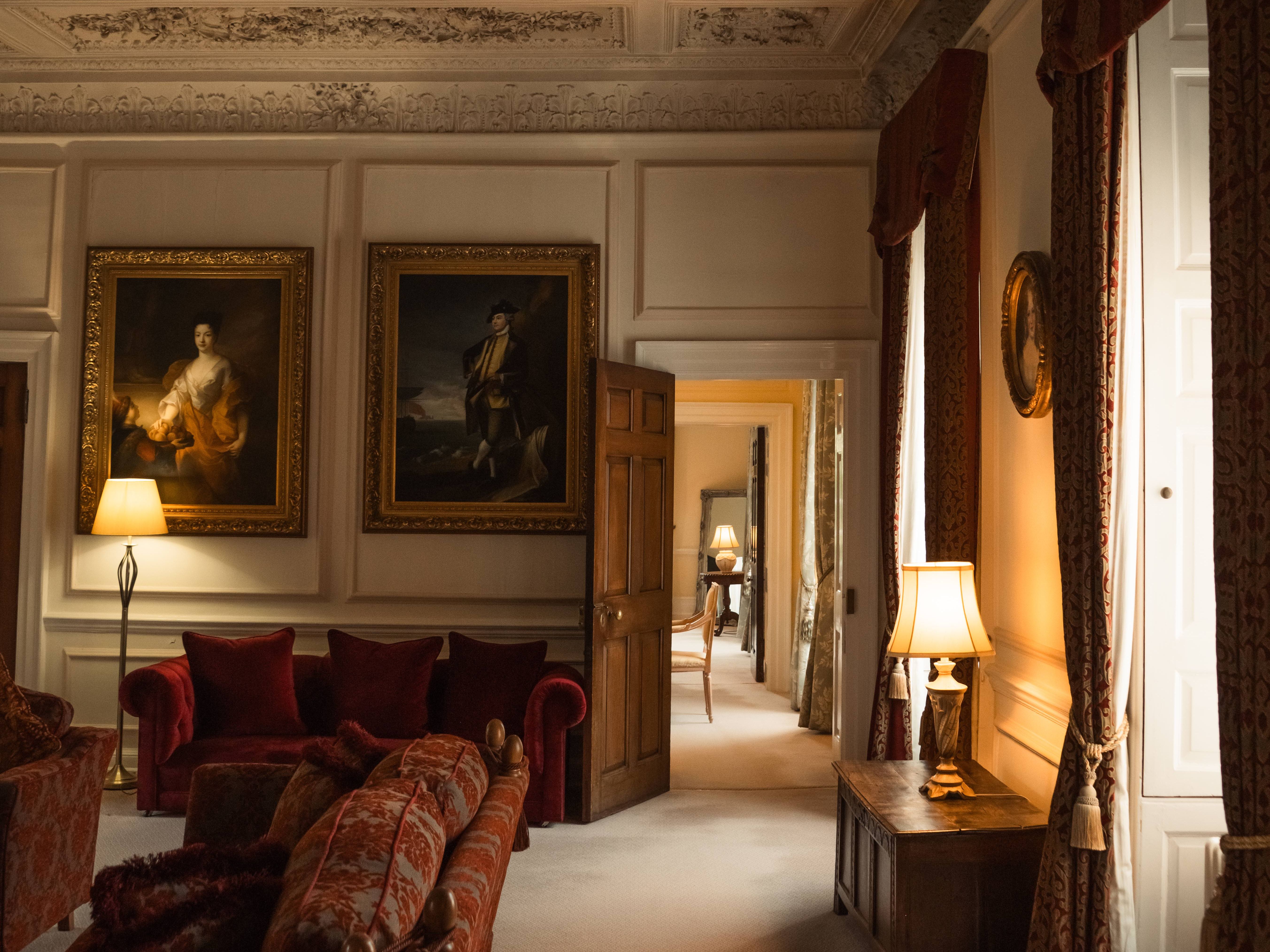 Elegant historical living room with ornate ceiling, vintage furniture, and classical paintings.