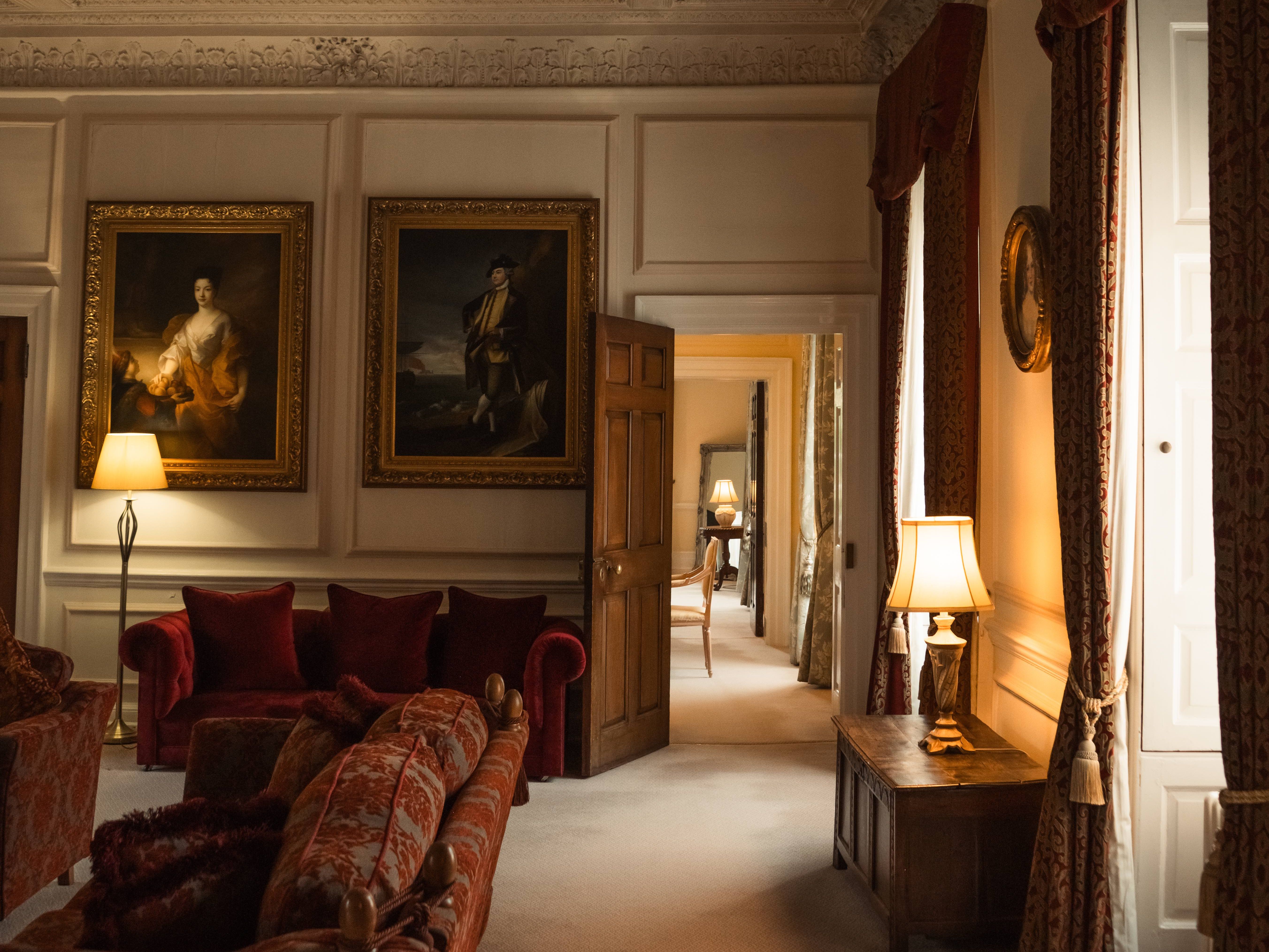 Elegant historical living room with ornate ceiling, vintage furniture, and classical paintings.