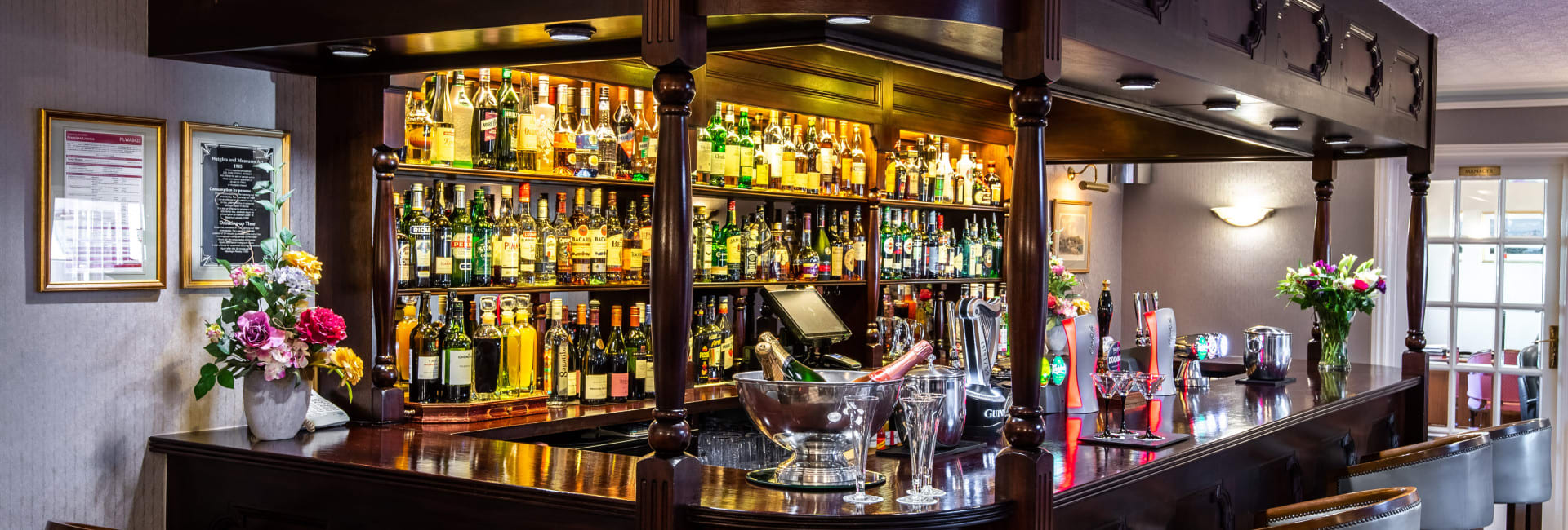 Bar stools around bar with bottles lit up
