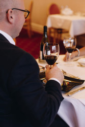 Guest drinking glass of wine in dining room
