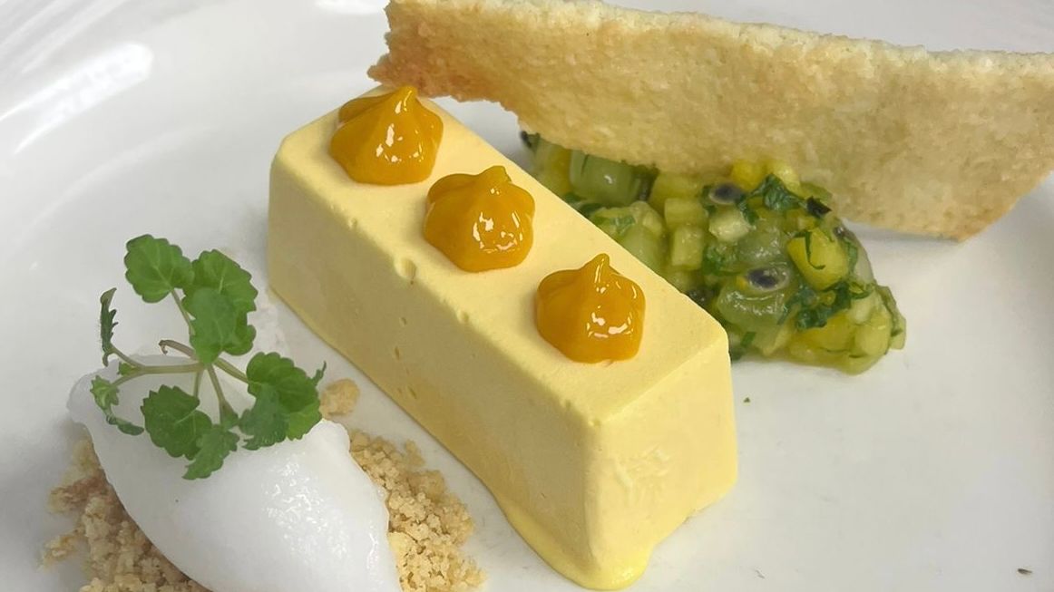 Gourmet plated dessert with mousse, fruit, sorbet, crumble, and a crisp tuile