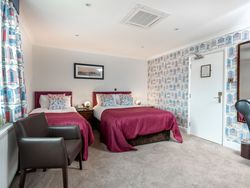 Twin room with two beds, patterned wallpaper, colorful curtains, and a cozy ambiance.