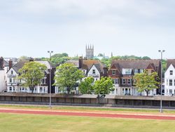 Row of houses behind a track field with a church tower in the background