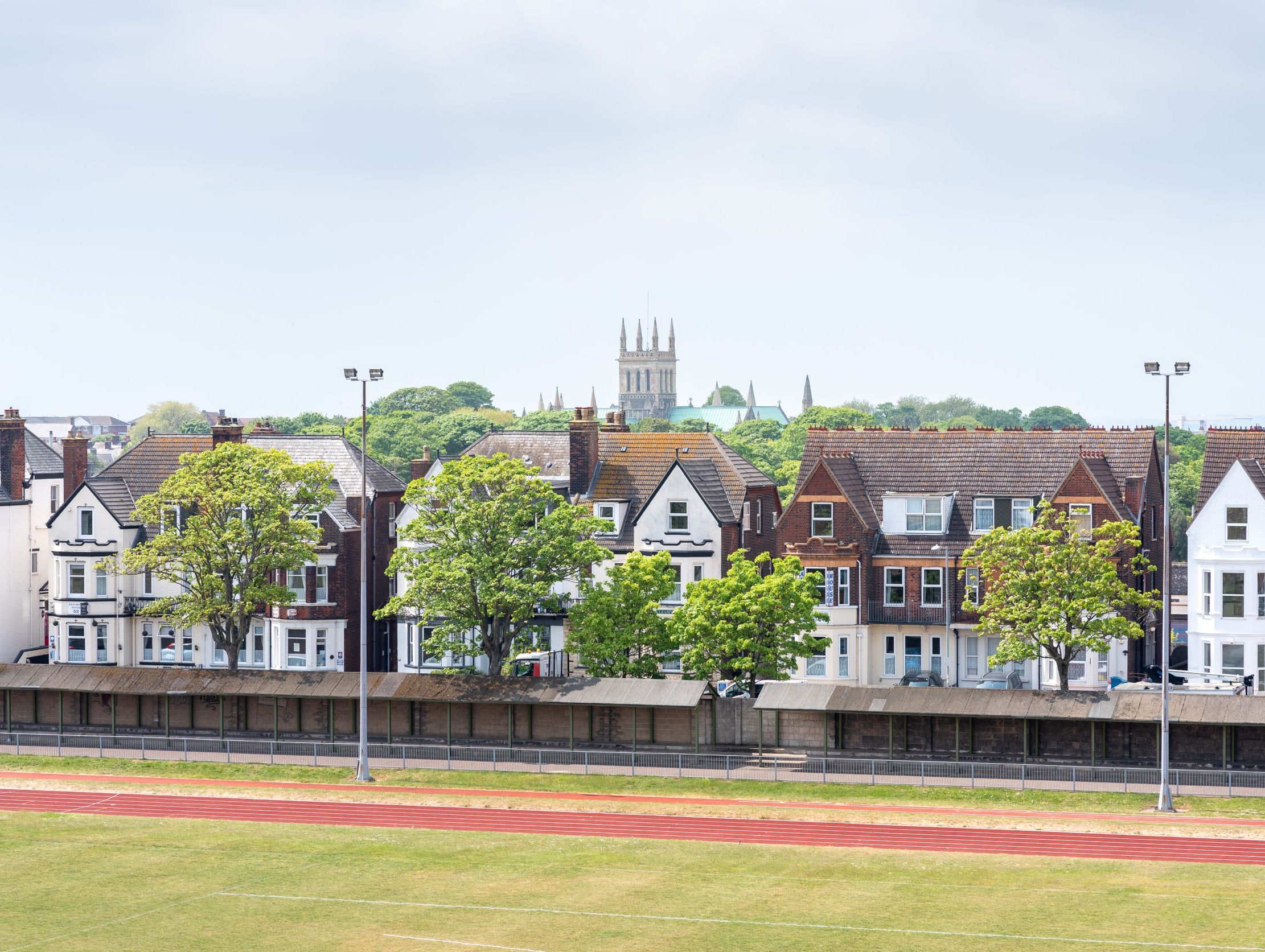 Row of houses behind a track field with a church tower in the background